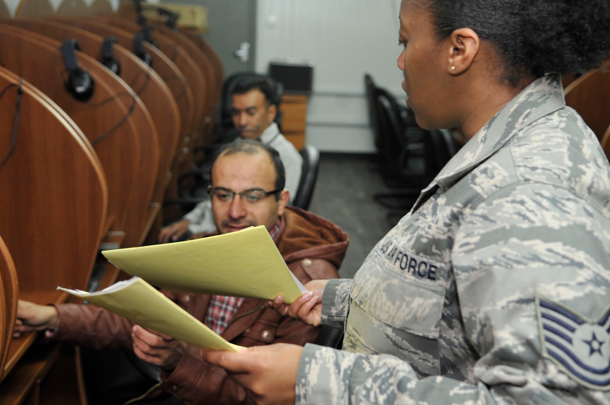 BAGHDAD, Iraq – U.S. Air Force Tech. Sgt. Fatema Tahan, Iraq Security Assistance Mission English Language Program test administrator, hands an exam to an Iraqi Air Force officer at Forward Operating Base Union III, International Zone, here Feb. 6. (U.S. Air Force photo by Senior Master Sgt. Larry Schneck/Released)