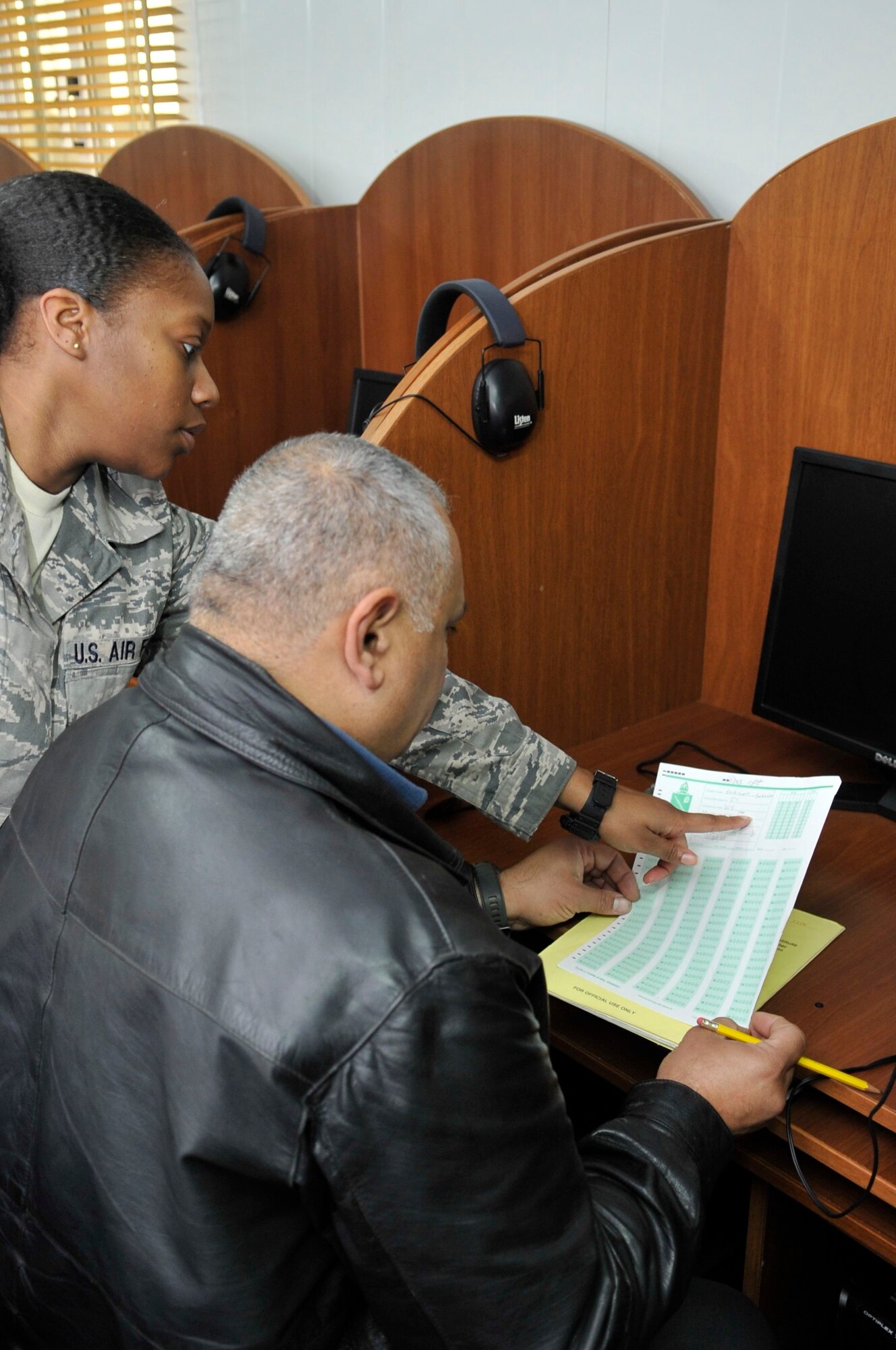 BAGHDAD, Iraq – U.S. Air Force Tech. Sgt. Fatema Tahan, Iraq Security Assistance Mission English language program test administrator, looks over the shoulder of an Iraqi Air Force officer as he fills out the administrative portion of the American Language Course Placement Test answer sheet inside the testing trailer at Forward Operating Base Union III, International Zone, here Feb. 6. (U.S. Air Force photo by Senior Master Sgt. Larry Schneck/Released)