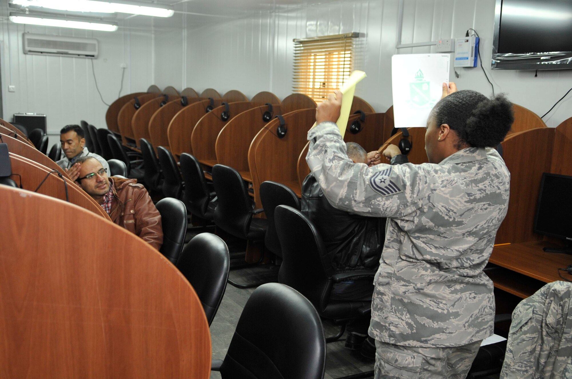 BAGHDAD, Iraq – U.S. Air Force Tech. Sgt. Fatema Tahan, Iraq Security Assistance Mission English Language Program test administrator, displays the test materials each examinee should have before he takes the American Language Course Placement Test at Forward Operating Base Union III, International Zone, here Feb. 6. (U.S. Air Force photo by Senior Master Sgt. Larry Schneck/Released)