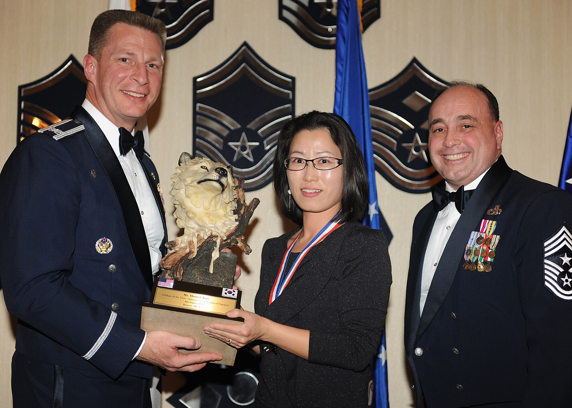KUNSAN AIR BASE, Republic of Korea -- Col. John Dolan, 8th Fighter Wing commander, and Chief Master Sgt. James Sanders, 8th Fighter Wing command chief, present Kim Hyonok, 8th Fighter Wing, with the 8th FW’s Category 2 Outstanding Civilian of the Year award. Mrs. Kim will go on to compete against annual winners from 7th Air Force on Feb. 26. (U.S. Air Force photo/Senior Airman Ciara Wymbs)  