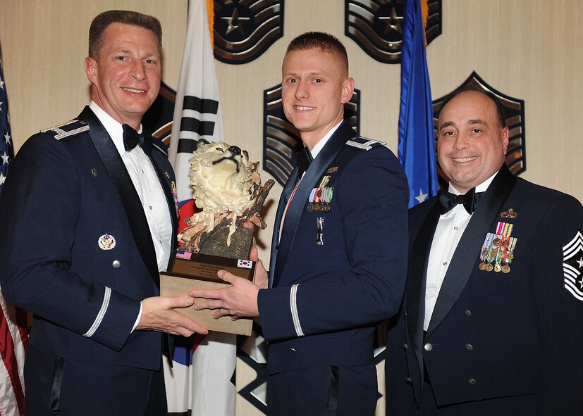 KUNSAN AIR BASE, Republic of Korea -- Col. John Dolan, 8th Fighter Wing commander, and Chief Master Sgt. James Sanders, 8th Fighter Wing command chief, present Capt. Cory Helms, 8th Maintenance Squadron, with the 8th FW’s Company Grade Officer of the Year award. Captain Helms will go on to compete against annual winners from 7th Air Force on Feb. 26. (U.S. Air Force photo/Senior Airman Ciara Wymbs)  