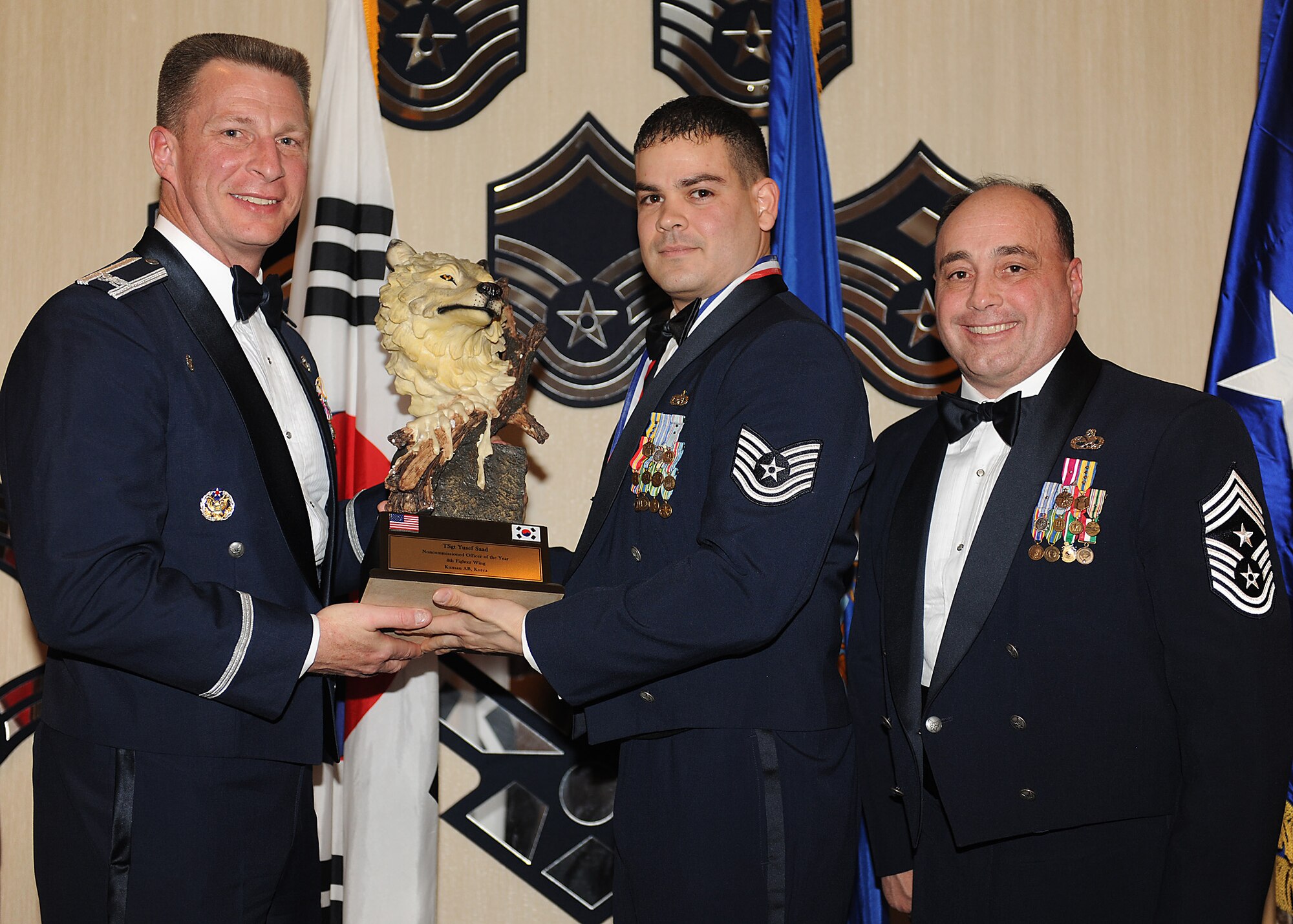 KUNSAN AIR BASE, Republic of Korea -- Col. John Dolan, 8th Fighter Wing commander, and Chief Master Sgt. James Sanders, 8th Fighter Wing command chief, present Tech. Sgt. Yusef Saad, 8th Logistics Readiness Squadron, with the 8th FW’s NCO of the Year award. Sergeant Saad will go on to compete against annual winners from 7th Air Force on Feb. 26. (U.S. Air Force photo/Senior Airman Ciara Wymbs)  