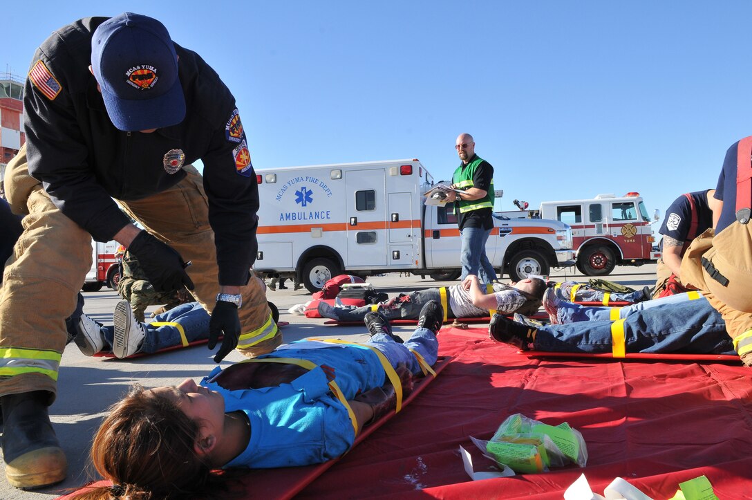 Station firemen assess the wounds of simulated victims during Exercise Desert Impact on the station flight line at the Marine Corps Air Station in Yuma, Ariz., Feb. 14, 2010. More than 400 Marines, sailors and civilians participated in the event, which called for station collaboration with civilian and federal agencies to diffuse a simulated scenario in which a terrorist shot down an aircraft during the station’s annual air show.