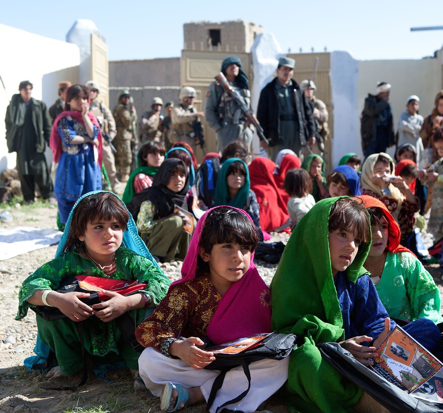 Local girls gather for the ribbon cutting of the Laki Girls School, in Garmsir district, Helmand province, Afghanistan, while coalition forces provide security, Feb. 15. According to Lt. Col. Matthew Reid, the commanding officer of 2nd Battalion, 1st Marine Regiment, improved security provided by coalition enforces enabled locals to defy the Taliban by establishing the girls school.