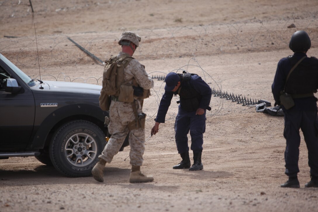 A role player, acting as a member of the Afghan National Army uses a mirror to look underneath a vehicle  at a vehicle inspection checkpoint,  at the Combat Center’s new combined arms, live-fire, Military Operations on Urban Terrain training range here, as part of Enhanced Mojave Viper, Feb. 15, 2011.  Vehicle checkpoints provide security and help to prevent vehicle born improvised explosive attacks, while in country.