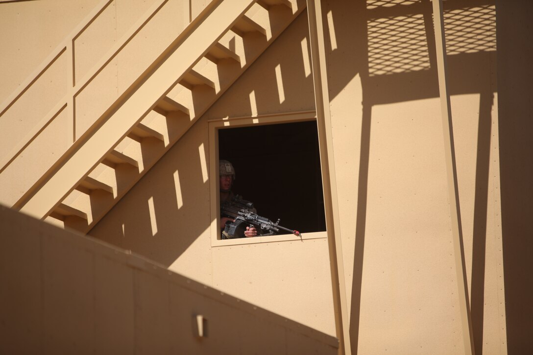 A Marine with  1st Battalion, 5th Marine Regiment, gets a bird’s eye view from a window overlooking an alley  at the Combat Center’s new combined arms, live-fire, Military Operations on Urban Terrain training range, in search of improvised explosive devices  as part of Enhanced Mojave Viper, Feb. 15, 2011.