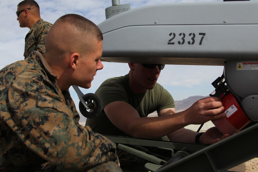 Corporal Quinn Austen Schwehr, a unmanned aerial vehicle maintainer with VMU-1, instructs Cpl. Cody Bowdoin, a UAV maintainer, how the RQ-7B Shadow works at the VMU-1 airfield Feb. 15, 2011.