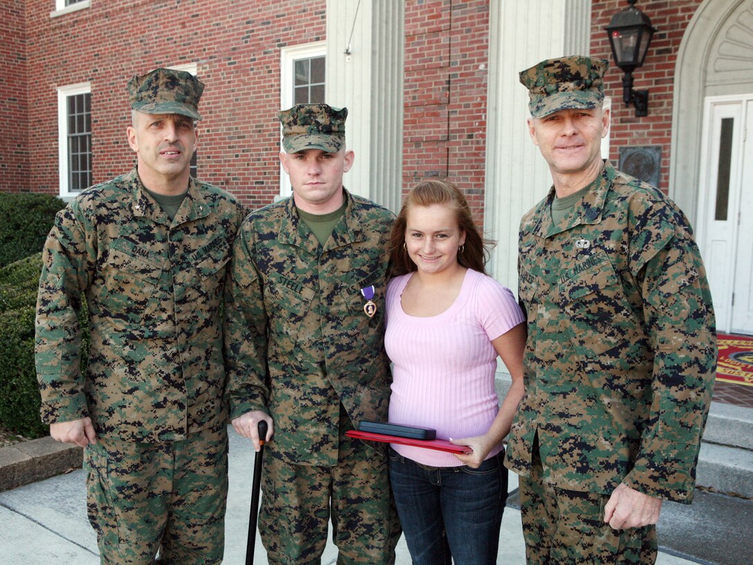 Lance Cpl. Brian K. Steele, a combat engineer with 2nd Marine Logistics Group, poses for a photo with his wife, Brig. Gen. Michael G. Dana, the command general for 2nd MLG, and Sgt. Maj. William T. Stables, the sergeant major for 2nd MLG, during his purple heart ceremony in front of the MLG Headquarter building aboard Camp Lejeune, N.C., Feb. 14, 2011. Steele was a vehicle commander during a convoy near Forward Operating Base Hansen when his vehicle struck an improvised explosive device. (U.S. Marine Corps photo by Pfc. Franklin E. Mercado)