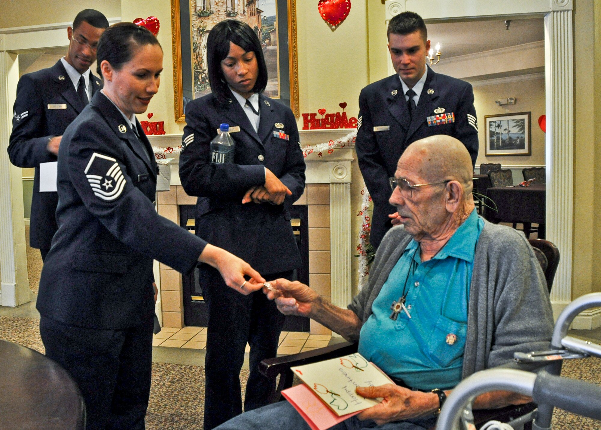 Master Sgt. Erika Follmar, 46th Test Wing, presents a lapel pin to Air Force veteran John Kuhelthau Feb. 14, during her visit to Wellington Place in Fort Walton Beach, Fla.  Master Sgt. Follmar joined more than 200 Eglin Airmen who presented homemade valentines and flowers to local retirement home residents.  (U.S. Air Force photo/Kevin Gaddie)