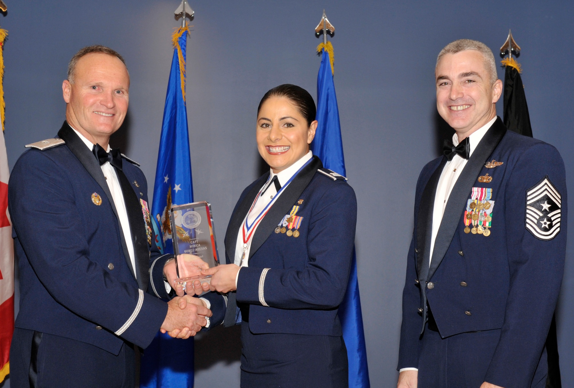 Brigadier Gen. James Browne, 325th Fighter Wing commander, and Chief Master Sgt. Jackie Green, 325th FW command chief, present the award for company grade officer of the year to Capt. Monica Gomez-Arenas, 325th Medical Support Squadron, during the Tyndall Annual Awards night. (U.S. Air Force photo/Jonathan Gibson)