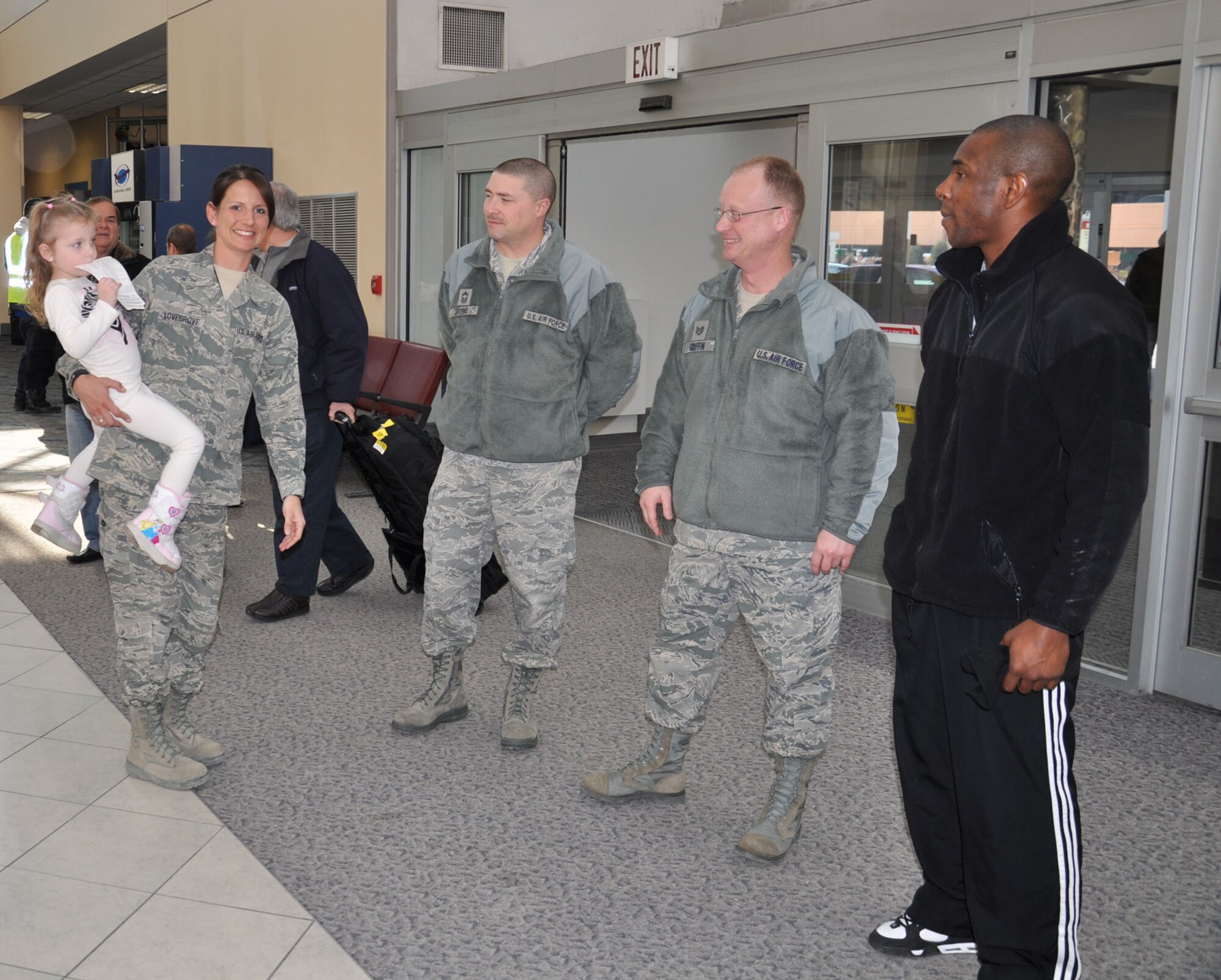WRIGHT-PATTERSON AIR FORCE BASE, Ohio - Tech. Sgt. Leslie Lovegrove, 87th Aerial Port Squadron, carries her niece, Hannah, as she receives a warm welcome home from her 87 APS co-workers Chief Master Sgt. Sean Storms, Tech. Sgt. Donald Griffin and Senior Airman Justin George, at the Dayton International Airport Feb. 11 after returning home from a 4-month deployment to Joint Base Balad. (U.S. Air Force photo/Lt. Col. Cynthia Harris)