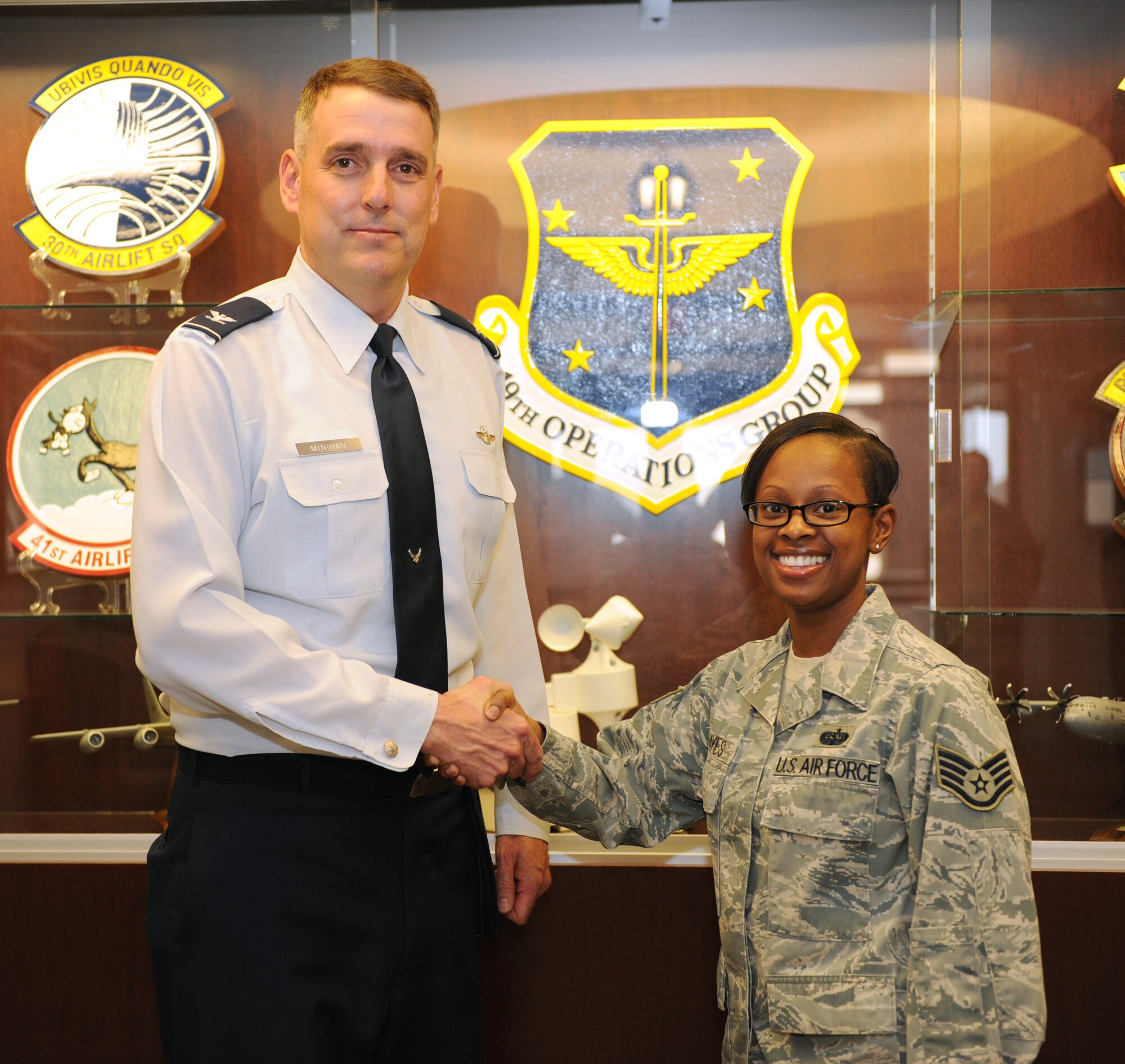 Col. Mike Minihan, 19th Airlift Wing commander, presents a coin Feb. 14, 2011, to Staff Sgt. Natasha Hayes, a 19th Operations Group knowledge operations manager, for her selection as the Combat Airlifter of the Week at Little Rock Air Force Base, Ark. Sergeant Hayes inspects and approves file plans for 19th Operations Group and keeps the group front office up and running. (Air Force photo by Airman 1st Class Ellora Stewart)