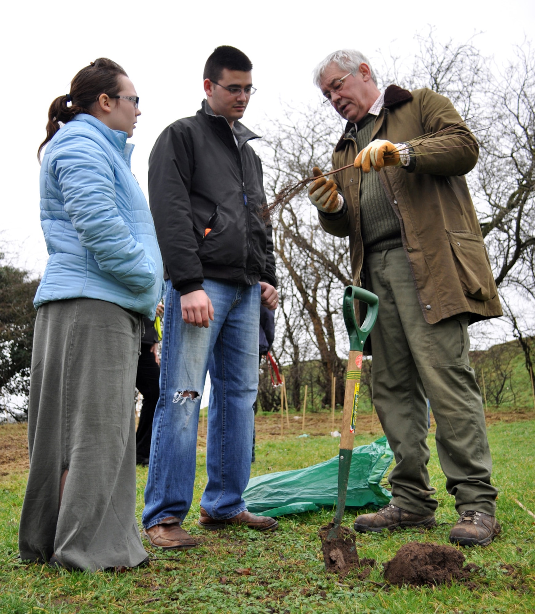 NEWMARKET, England -- Grenville Clarke, Green Light Trust, gives Airman 1st Class Samuel Devalal, 48th Communications Squadron, and his wife Katie, a demonstration in tree planting, Feb. 12, 2011, during "Go Wild in Newmarket's" Tree and Hedge Planting Extravaganza.  Green Light Trust helps local wildlife groups like Go Wild in Newmarket get up and running, and assists with events such as this one. The event was aimed at planting 1,500 trees to form a wildlife hedge.  More than 50 volunteers, including members from RAFs Lakenheath and Mildenhall, came out to participate.  (U.S. Air Force photo/Tech. Sgt. Marelise Wood) 