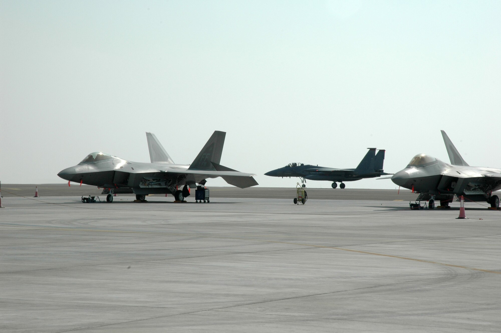The 94th Expeditionary Fighter Squadron's F-22 Raptors stand in the foreground as the 67th Expeditionary Fighter Squadron?s F-15Cs taxied in recently. The 67th EFS is deployed from Kadena AFB, Japan. (U.S. Air Force photo by Master Sgt. Julie Briden-Garcia) 