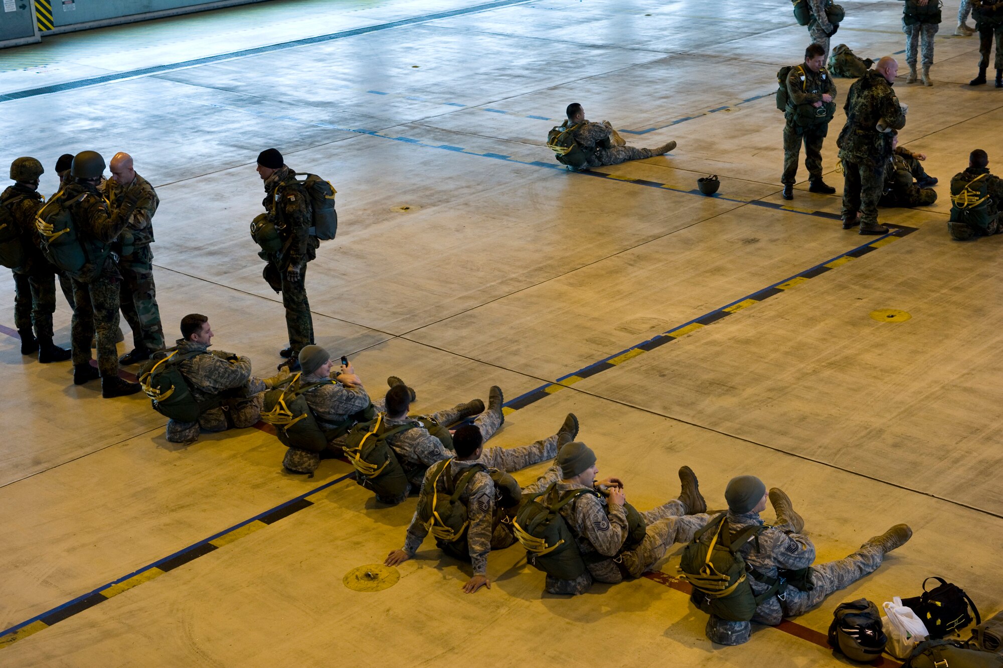 U.S. Army Soldiers, Air Force Airmen and German soldiers wait in a hanger before loading into a C-130J Hercules, from Ramstein Air Base, Germany, in preparation for a training airdrop mission at the Marnheim, Germany drop zone, Feb. 10, 2011. The single C-130J aircraft from the 37th Airlift Squadron, 86th Airlift Wing dropped more than fifty service members at the drop site.  (U.S. Air Force photo/TSgt Wayne Clark, AFNE Regional News Bureau) (Released)