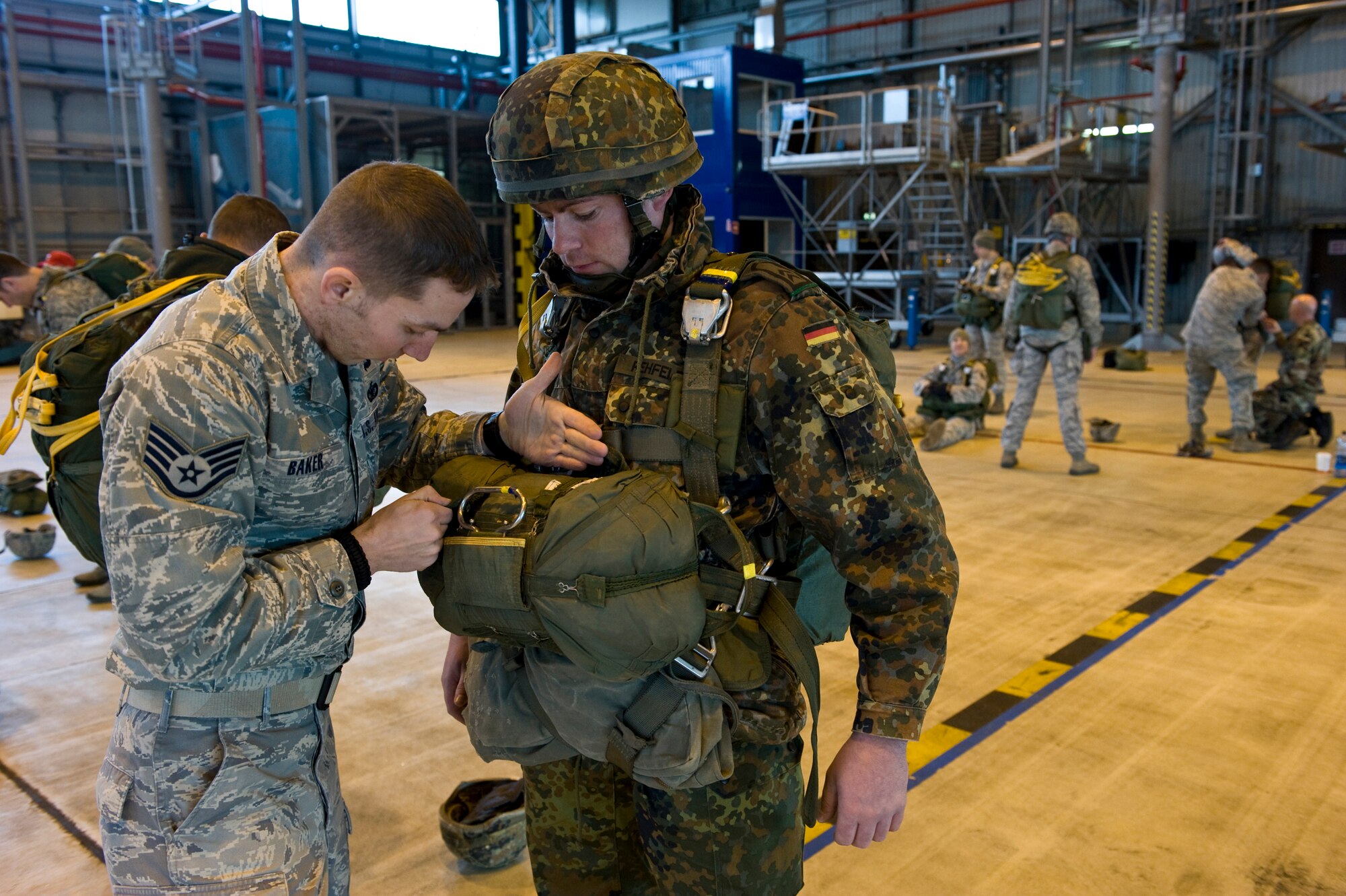 Staff Sergeant Stephen Baker, NCOIC Air Operations, 435th Security Forces Squadron, checks the parachute of a German soldier before loading onto a C-130J Hercules, from Ramstein Air Base, Germany, in preparation for a training airdrop over drop zone Marnheim, Germany, Feb. 10, 2011. The single C-130J aircraft from the 37th Airlift Squadron, 86th Airlift Wing dropped more than fifty service members at the drop site.  (U.S. Air Force photo/TSgt Wayne Clark, AFNE Regional News Bureau) (Released)