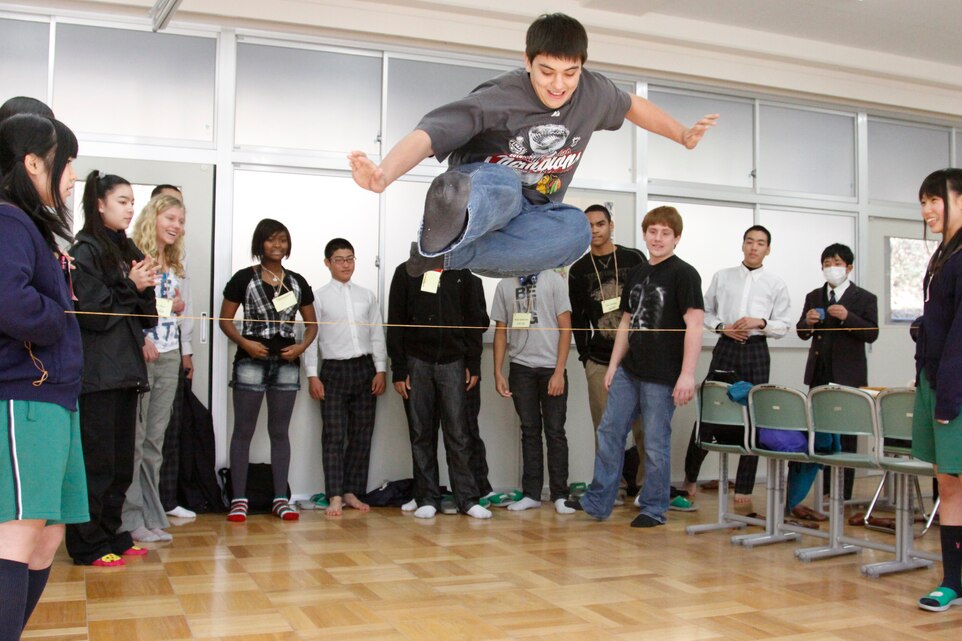 Charles Van Allen, a Matthew C. Perry High School student, launches over a string during a reverse limbo game at Takamori Midori Junior High School Feb. 16. The reverse limbo game was one of several planned activities that helped bring the Japanese and American high school students to understand each other’s cultures in a fun and friendly way.