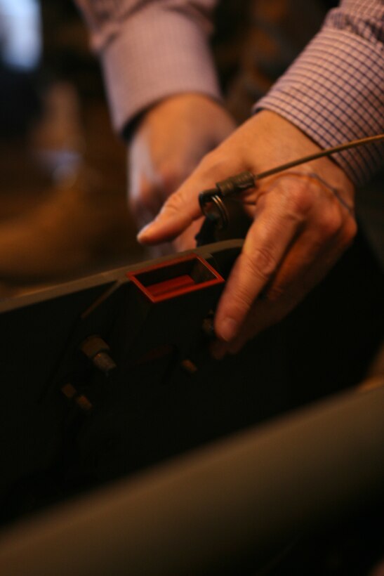Robert Speaker, instructor of the Humvee Egress Awareness Training, removes the latch to the gunner’s hatch of the simulator here Feb. 16 to demonstrate how difficult it is to::r::::n::move and hold in place while holding the hatch open. Marines were tasked with quickly evacuating from the gunner’s hatch or side hatches in less than four minutes.