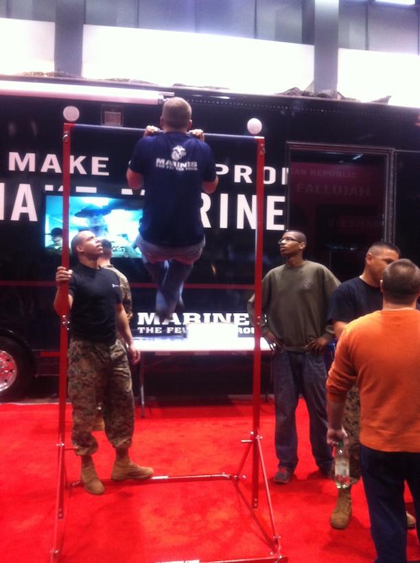 Visitors at the 2011 Chicago Auto Show attempt pull-ups outside the 9th Marine Corps Districts new trailer. In addition to portable pull-up bars the trailer has an Indoor Simulated Marksmanship Trainer and a modified tactical Humvee.