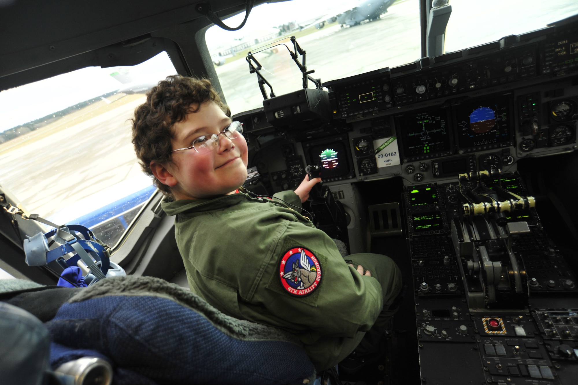 Nine-year-old Owain Weinert smiles as he sits in the pilot seat of a C-17 Globemaster III as part of the Pilot for a Day program Feb. 15 at Joint Base Lewis-McChord, Wash. Pilot for a Day is an Air Force program that enables challenged youth a chance to visit an Air Force squadron, becoming part of the team in the process. (U.S. Air Force photo/Airman 1st Class Leah Young)