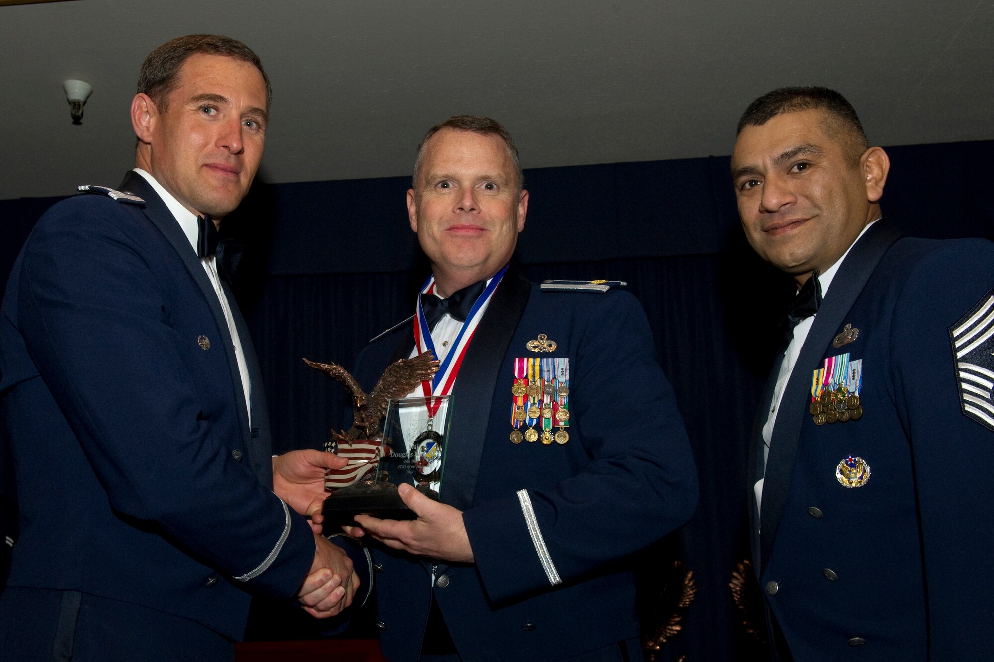 HOLLOMAN AIR FORCE BASE, N.M. -- Maj. Douglas Warren, 49th Maintenance Group, receives the Field Grade Officer of the Year award from Col. David Krumm, 49th Wing commander, during the Wing’s Annual Awards Ceremony, Feb. 11. Major Warren deployed 188 days to Kabul, Afghanistan, where he aggressively sourced $93 million in aircraft parts, which enabled the Afghan air force to operate independently. Additonally, he procured upgraded body armor, ensuring maximum protection and eliminating flight control function limitations. The nominees for FGO of the Year were Major Warren; Maj. Anita Chapel, 49th Medical Group; Maj. Patrick Holland, 49th Mission Support Group; and Maj. Matthew Dean, 49th Operations Group. (U.S. Air Force photo by Airman 1st Class Eileen Payne and Airman 1st Class Joshua Turner/Released)