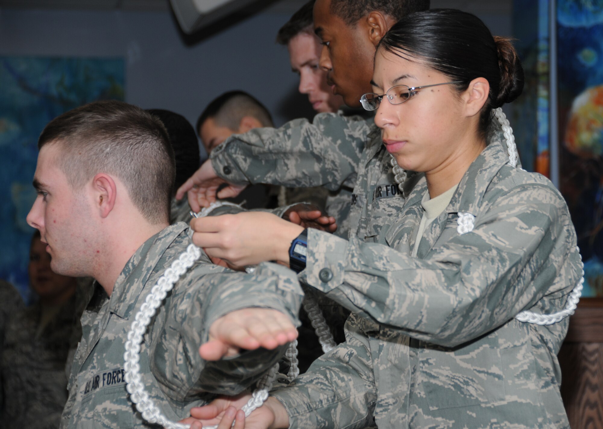 Airman Basic James Carver, 336th Training Squadron, has his white rope removed by Airman Basic Kellie-Jo Gomey, 336th TRS, during a ceremony at the Levitow Training Support Facility Jan. 19. During the “Roping Out” ceremony, students who are only a few weeks away from leaving Keesler have their ropes removed as the responsibilities move on to another student volunteer.  (U.S. Air Force photo by Kemberly Groue)