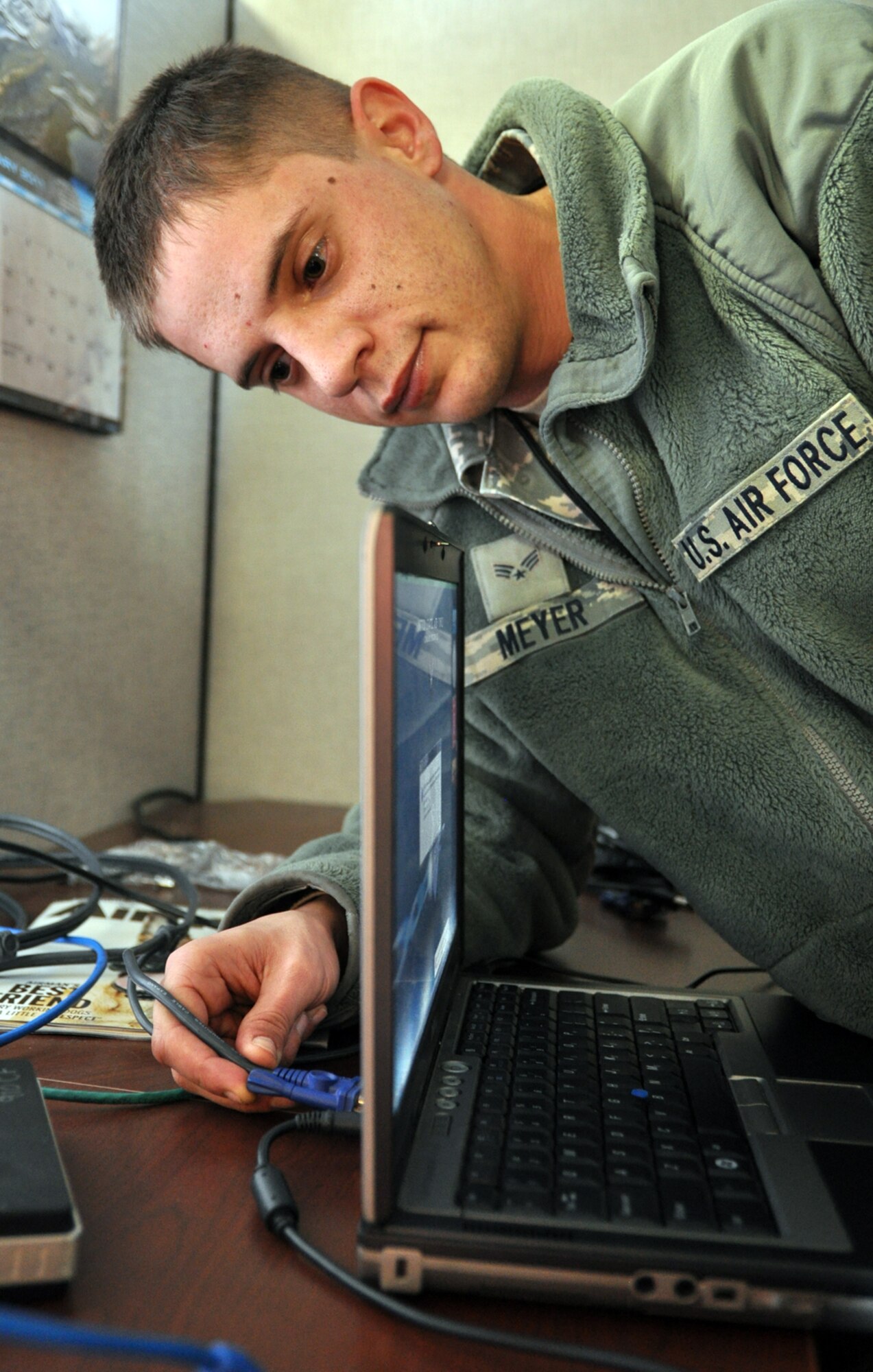 Air Force Reserve Senior Airman Mark Meyer, a client support technician assigned to the 910h Communications Flight, plugs a video monitor cord into the back of a laptop during the January Unit Training Assembly at Youngstown Air Reserve Station.
