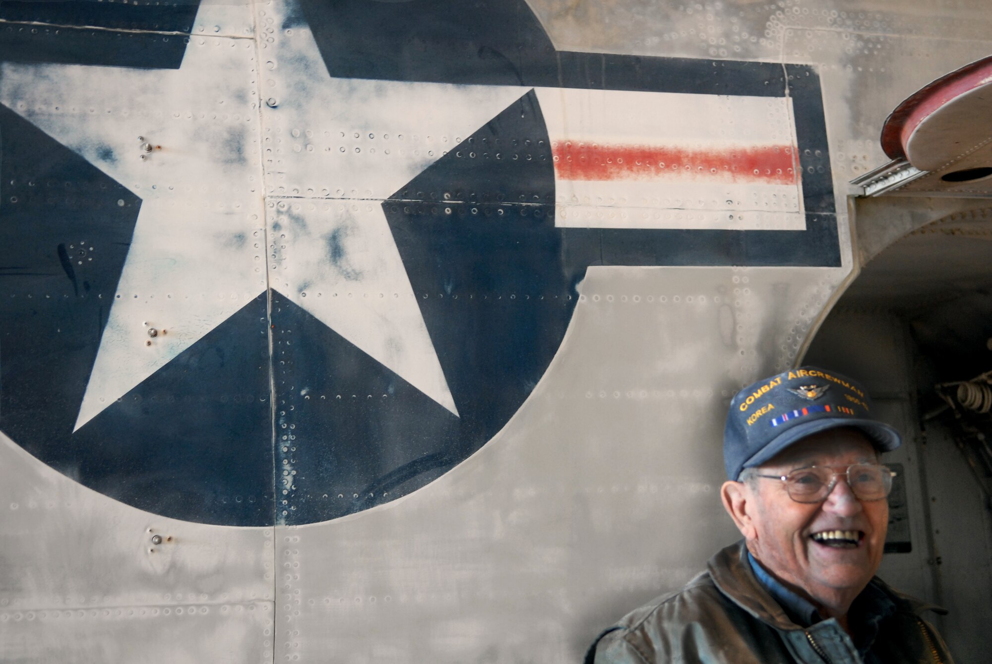 Clark Warren, retired Navy chief, takes a break from sanding to pose with the same A3D-1 Skywarrior he flew in while on active duty in the 1950s. Mr. Warren joined a 10-man group that is working to restoring the aircraft. They hope to preserve it at the Air Force Flight Test Center museum on base. (Air Force photo by Kate Blais)