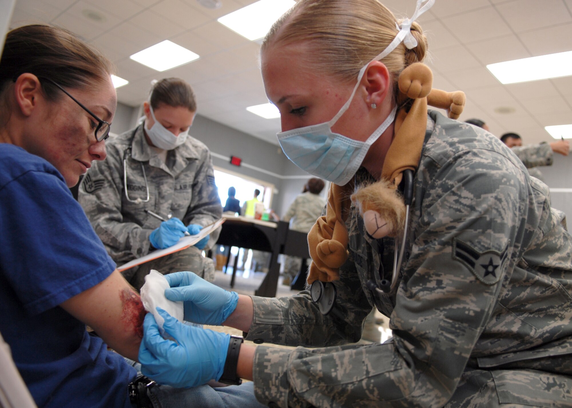 Airman 1st Class Jennifer Andrade, a 95th Medical Group medical technician, dresses the wound of a victim of a simulated explosion as Staff Sgt. Trisha Wiggins, 95th MDG medical technician, evaluates the patient as part of a basewide exercise Feb. 14. The exercise included several scenarios, such as a suspicious package and the explosion of a chemical bomb. The scenarios test the capabilities of the base?s emergency response teams. They also test each building?s ability to perform force protection measures. The exercise will wrap up with a phase one and two Operational Readiness Exercise. Phase one of the ORE tests the base?s ability to prepare Airmen for deployment and phase two evaluates a member’s ability to survive and operate in a deployed environment. (Air Force photo by Senior Airman William A. O'Brien)