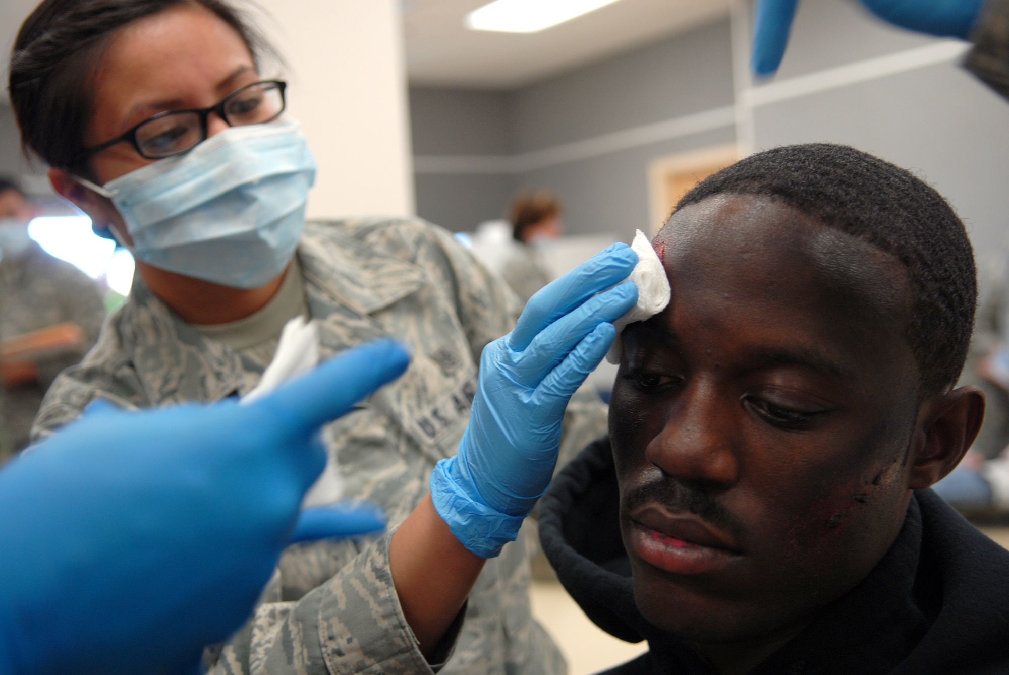 Airman 1st Class Julynn Guiwan, a 95th Medical Group medical technician, administers first aid to a victim of a simulated explosion during a basewide exercise Feb. 14. The exercise started at the Air Force Flight Test Center where a simulated explosion injured more than 50 people. Emergency responders treated and decontaminated the victims and transported them to the 95th Medical Clinic for additional care. (Air Force photo by Senior Airman William A. O’Brien)