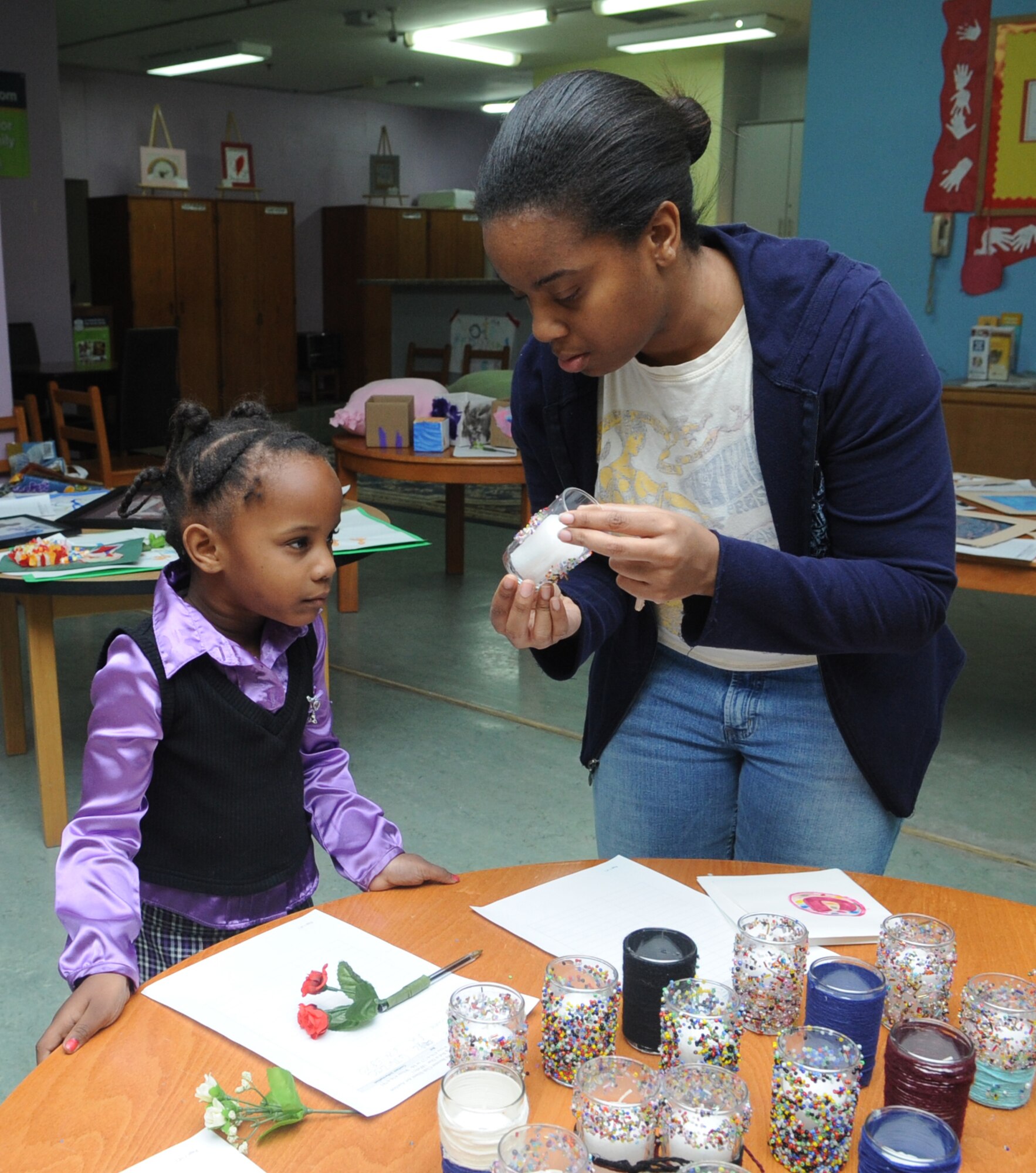 Staff Sgt. Irvona Page, from the 39th Medical Operations Squadron, and her daughter, Aniyah Page, decide the candle on which to place a bid, Feb. 11, 2011, at Incirlik Air Base, Turkey. The youth center held a silent auction with art created by children ages 4-12 from the youth center and the Child Development Center.  (U.S. Air Force photo by Tech. Sgt. Valda Wilson/Released)