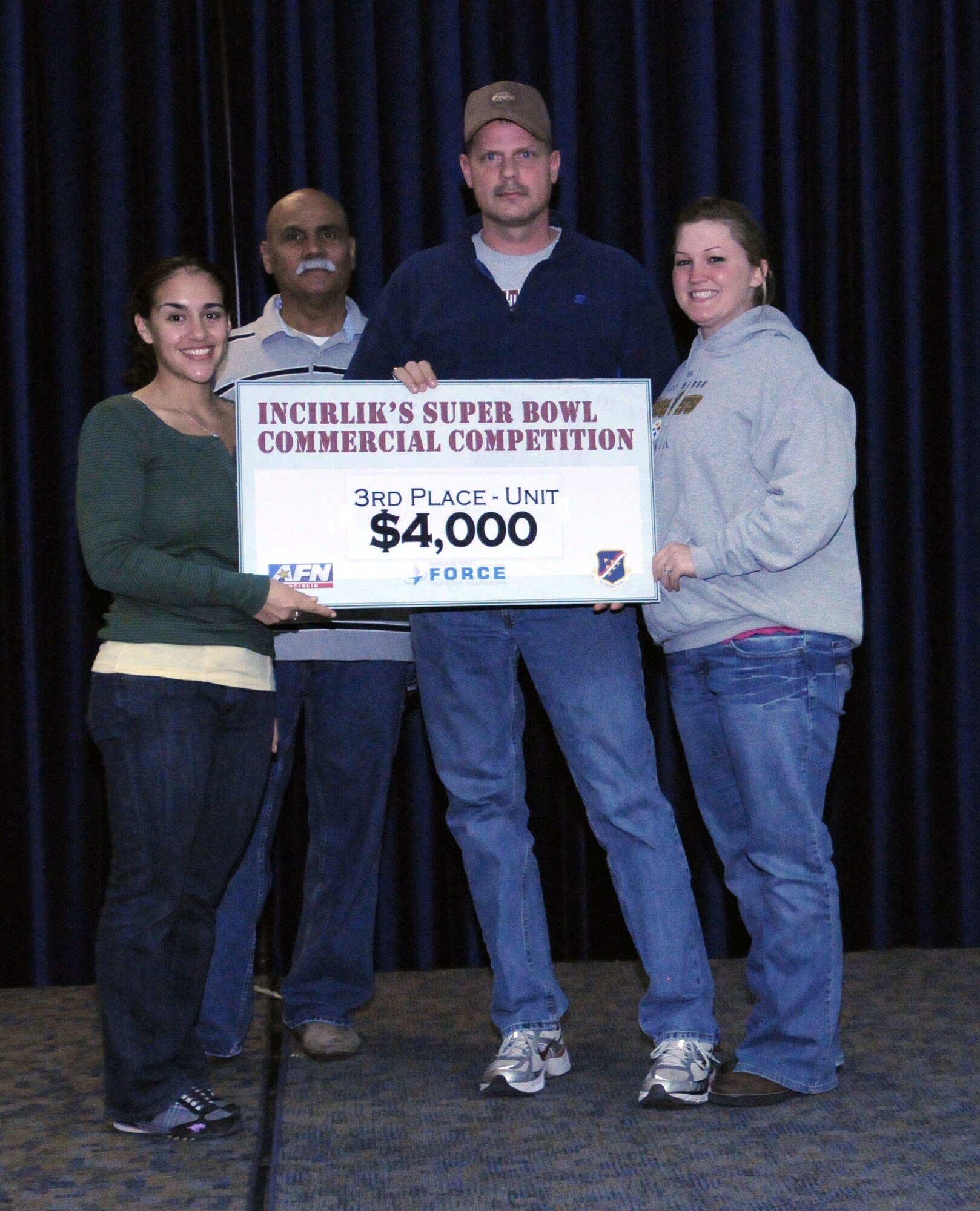 1st Lt. Gina McKeen, the 39th Air Base Wing public affairs chief, and Jorge Rodriguez, the consolidated club manager, present the $4,000 third-place prize to Airmen from the 39th Security Forces Squadron at the finale of the Incirlik Super Bowl commercial contest Feb. 7, 2011, at the consolidated club on Incirlik Air Base, Turkey. The event was held in conjunction with the Super Bowl XLV screening event Feb. 6-7, and attendees had the opportunity to view and vote for their favorite locally-produced commercial. The first- and second-place winners received $10,000 and $6,000 respectively. The prize money is to be used for quality-of-life programs within the units. (U.S. Air Force photo by Master Sgt. James Law/Released)