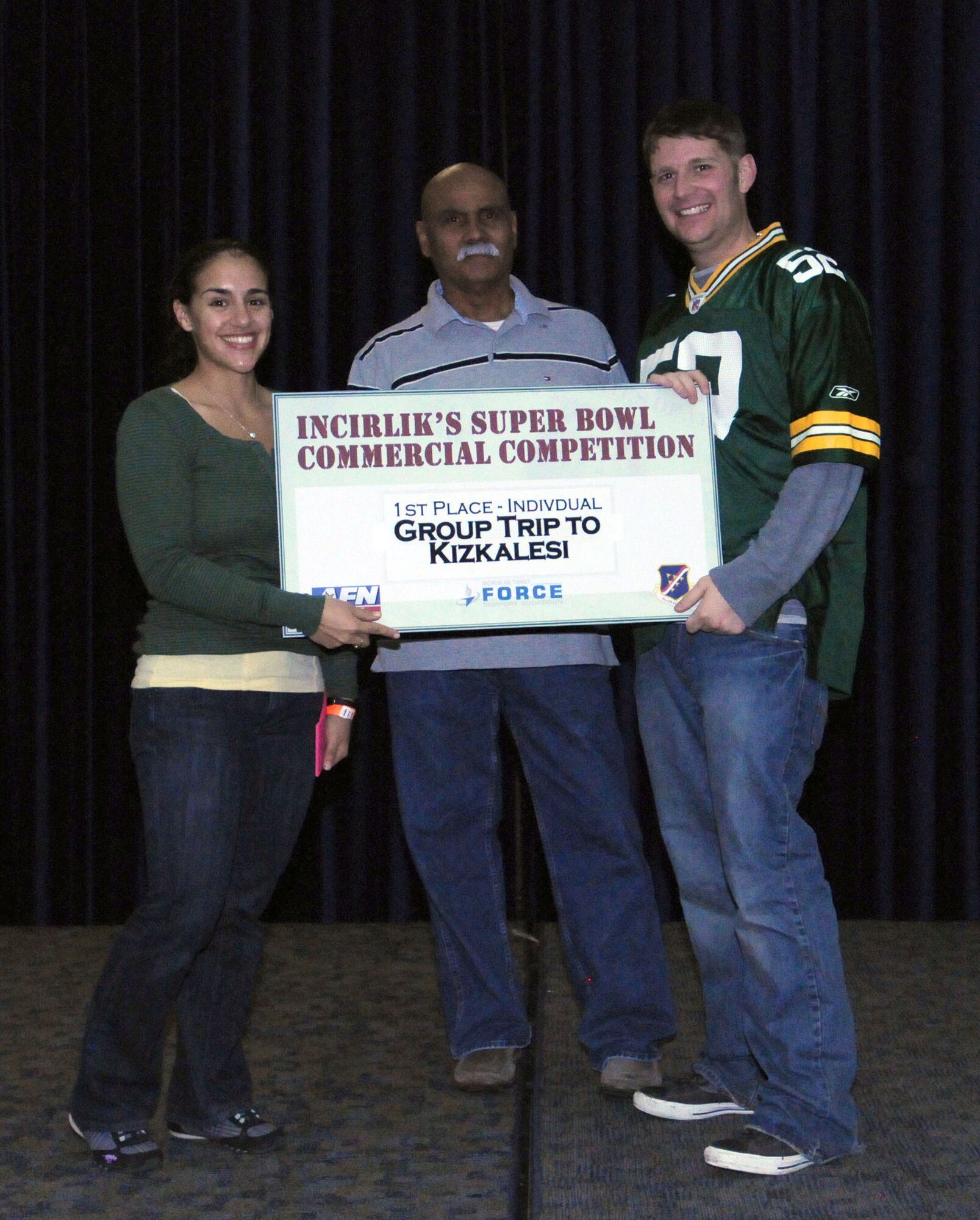 1st Lt. Gina McKeen, the 39th Air Base Wing public affairs chief, and Jorge Rodriguez, the consolidated club manager, present the prize to the individual category winner of the Incirlik Super Bowl commercial contest to Senior Airman Jonathan Smith, 39th Medical Operations Squadron, Feb. 7, 2011, at the consolidated club at Incirlik Air Base, Turkey. The event was held in conjunction with the Super Bowl XLV screening event Feb. 6-7.  Attendees had the opportunity to view and vote for their favorite locally-produced commercial. (U.S. Air Force photo by Master Sgt. James Law/Released)