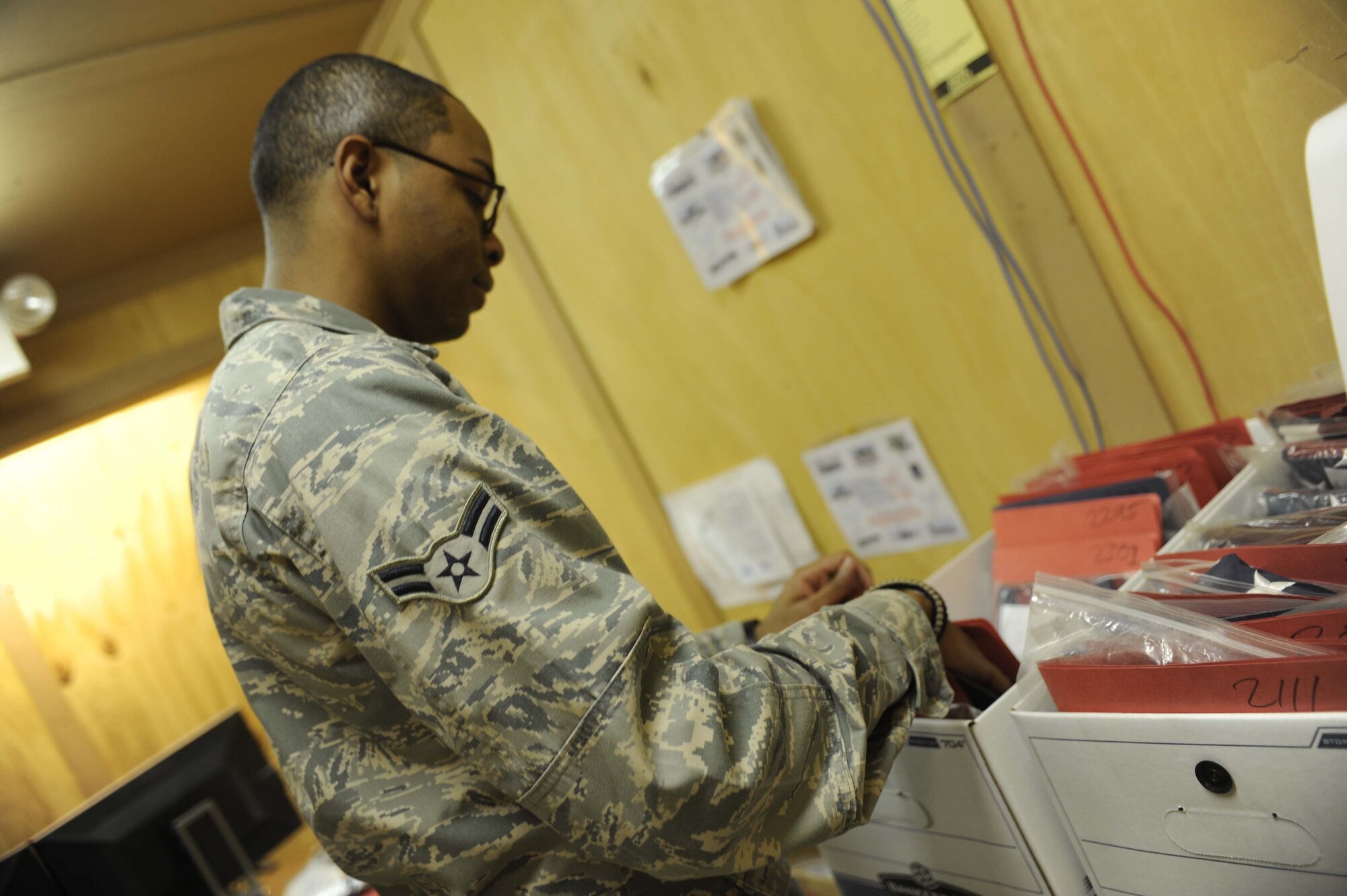 Airman 1st Class Joshua Williams organizes flags that are waiting to be flown on 451st AEW aircraft on Feb. 12, 2011, at Kandahar Airfield, Afghanistan. Airman Williams, manager of the flag flying program, tracks all the flags in the program program, which flew more than 3,000 flags in the past six months. (U.S. Air Force photo/ Tech. Sgt. Emily F. Alley)