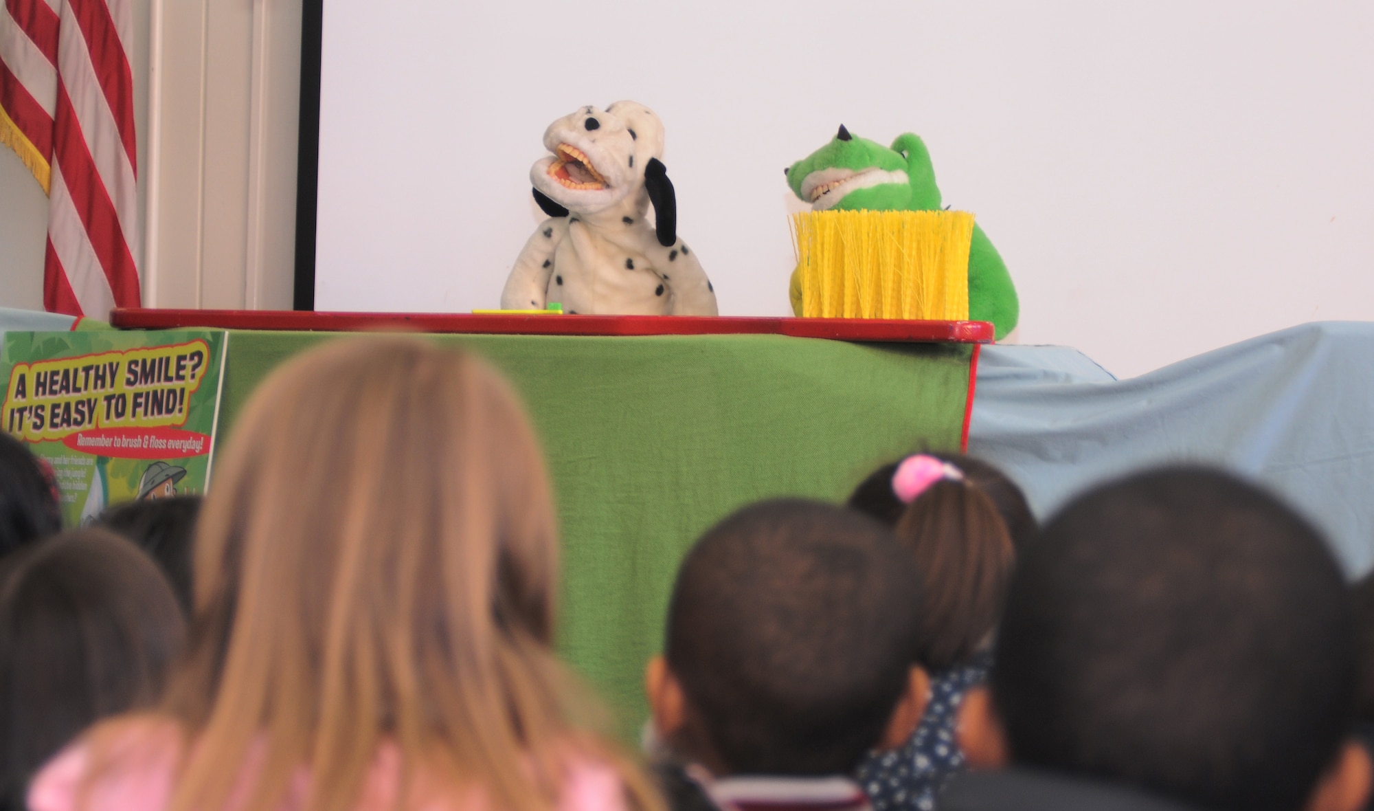 YOKOTA AIR BASE, Japan -- Daisy the Dog and Dudley the Dinosaur, tell kindergarten students from Joan K. Mendel Elementary School and Faith Kingdom Academy International from Fussa City, Japan, what tooth brushes are for and how to properly use them during a puppet show here Feb. 16. The children gathered at the end of the day to watch the show which summarized the dental hygiene practices they had learned during their visit to the 374th Dental Squadron dental clinic. (U.S. Air Force Photo/Airman John Partlow)