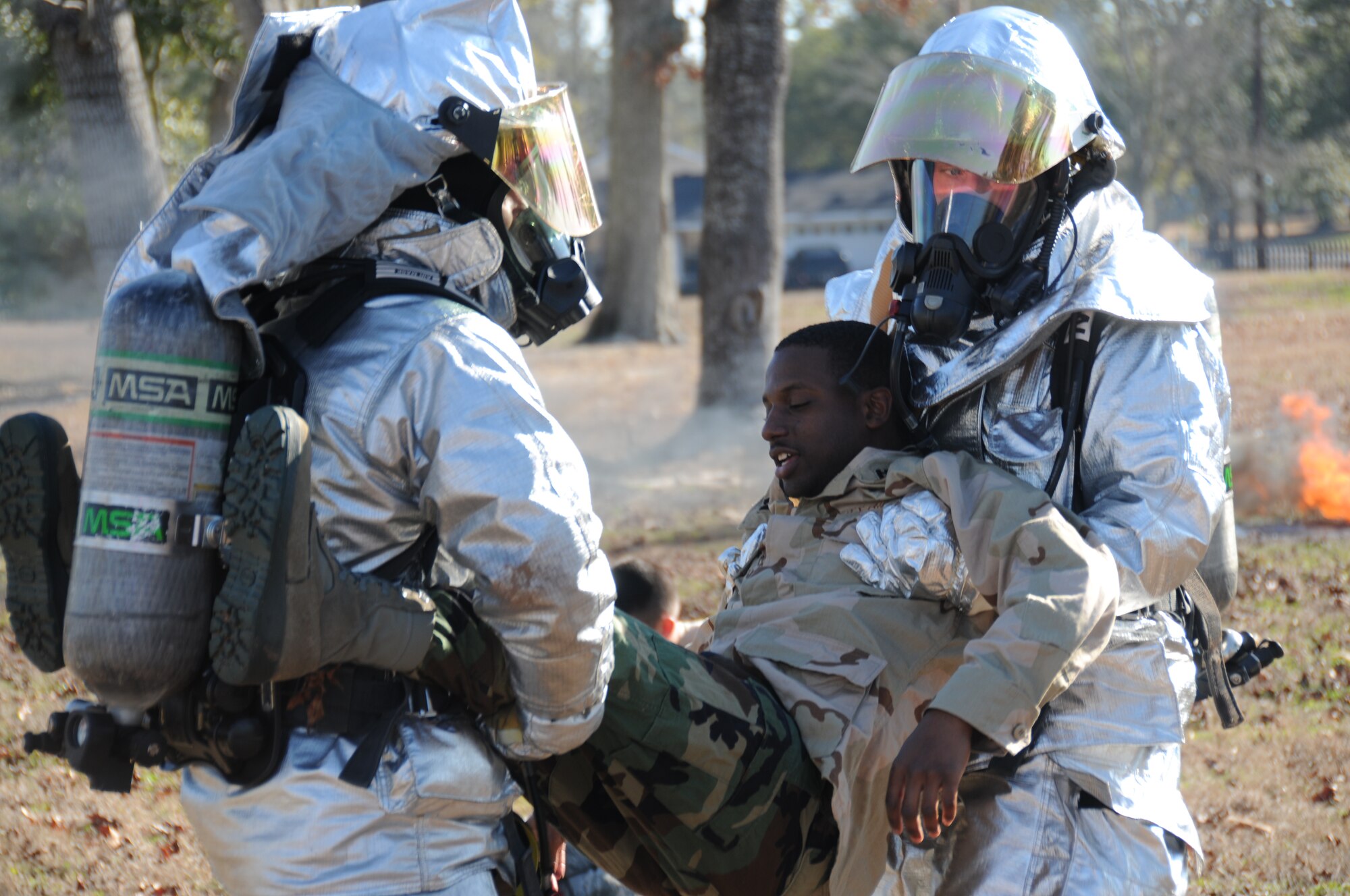 Keesler firmen carry Airman Basic Wayne Cotton Jr., 336th Training Squadron Student, to the Triage area to receive medical treatment for a leg injury during today’s exercise in which Keesler responded to a mid-air collision of two Blue Angel’s F-18’s.   (U.S. Air Force photo by Kemberly Groue)