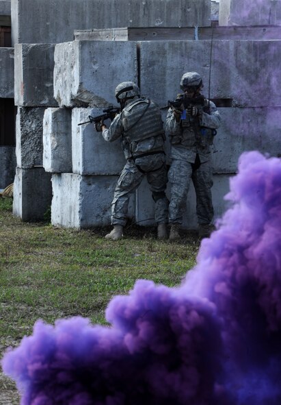 AVON PARK, Fla.-- Two Airmen from the 823rd Base Defense Squadron move positions behind a cover of purple smoke during joint exercise ATLANTIC STRIKE 11-01 Feb. 16. The 823rd BDS worked with joint forces to sweep the town of opposing forces and mark targets for participating aircraft to attack. (U.S. Air Force photo/Airman 1st Class Benjamin Wiseman)(RELEASED)