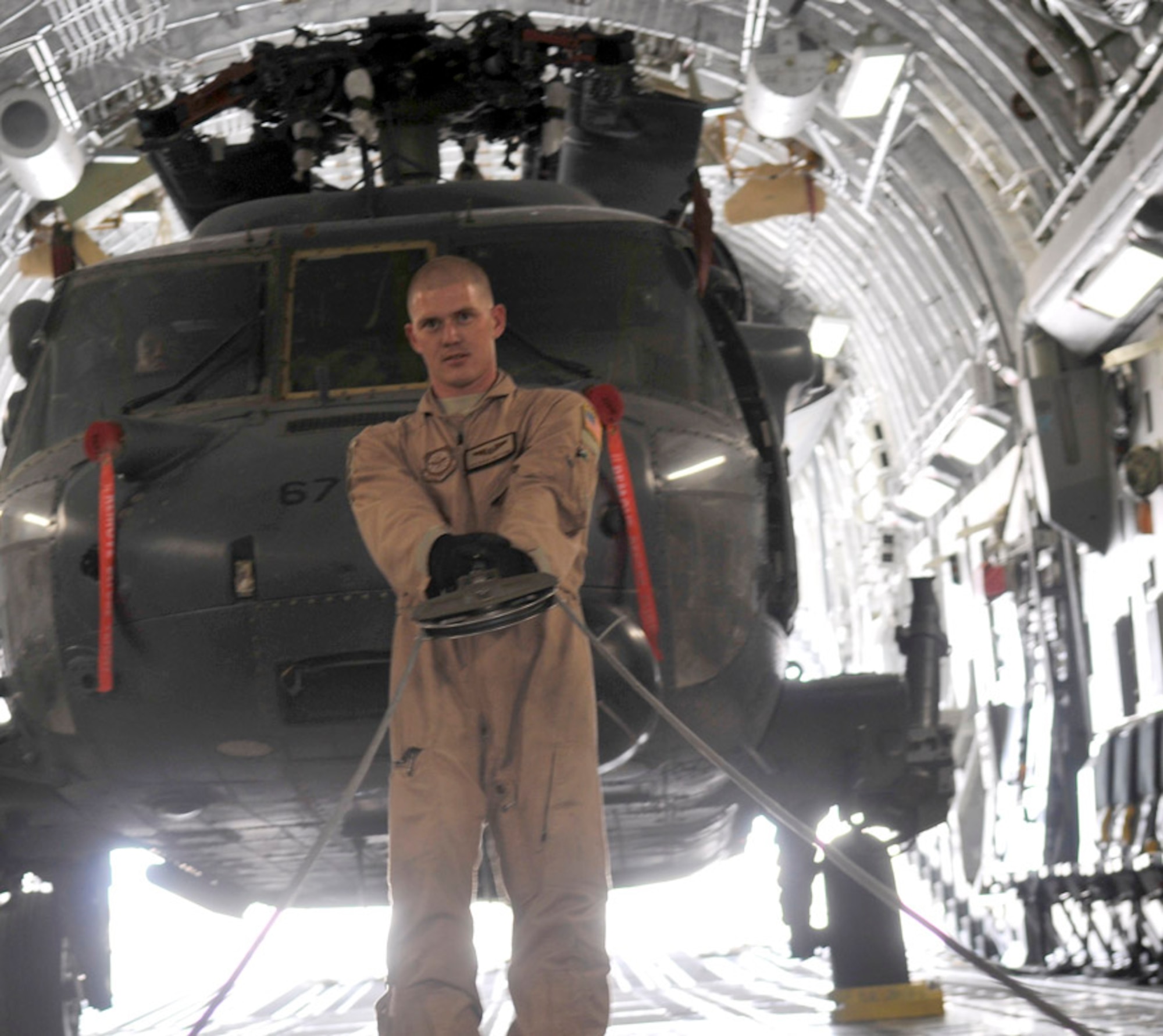 Airman 1st Class Brain Whitcomb pulls cable from a C-17 Globemaster III's deck pulley system to attach to an HH-60 Pave Hawk Aug. 12, 2010, at Joint Base Balad, Iraq. The C-17 can change its cargo bay to accommodate almost any load. Airman Whitcomb is a loadmaster assigned to the 10th Airlift Squadron. (U.S. Air Force photo/Staff Sgt. Phillip Butterfield)