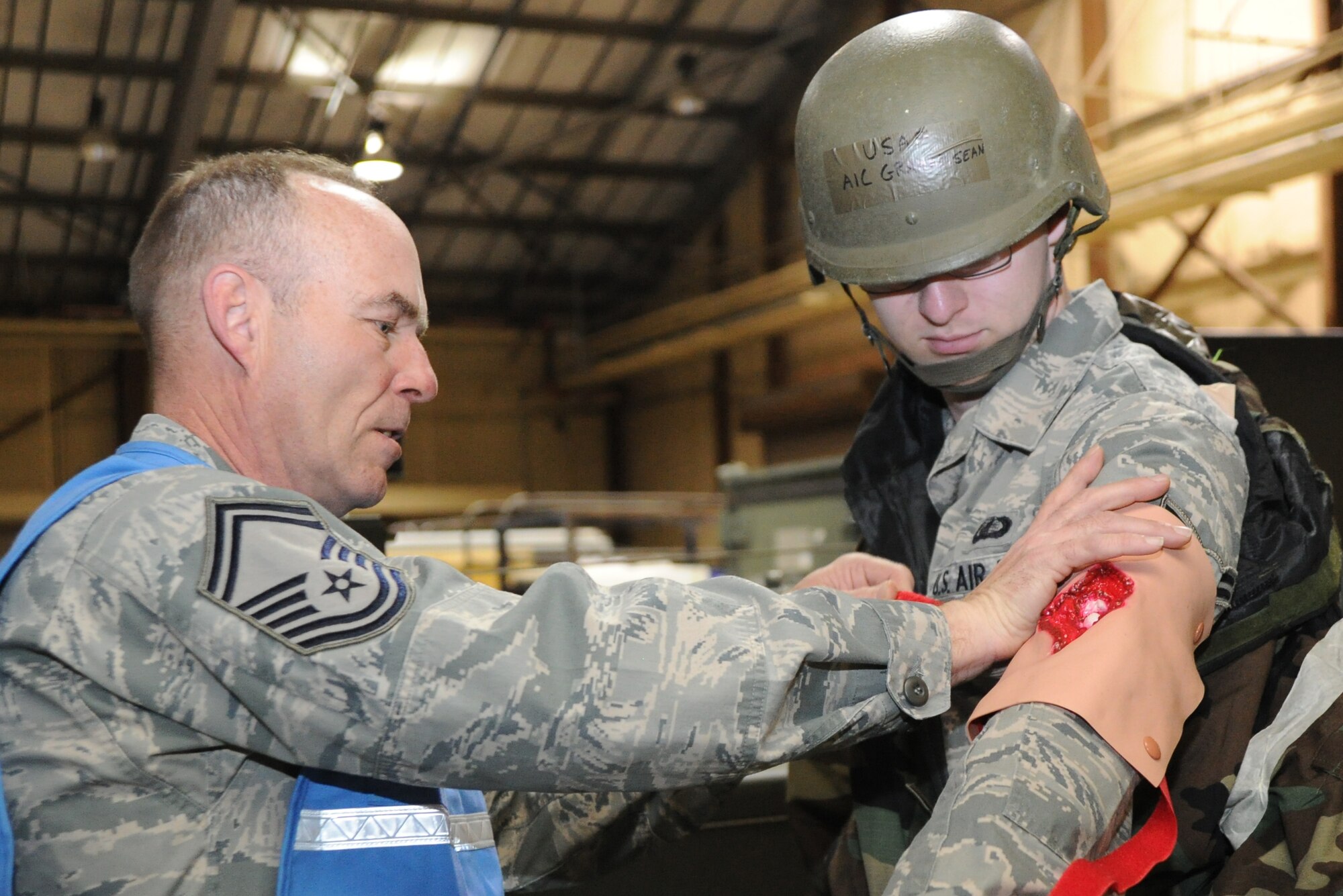 Senior Master Sgt. Charles Becker, 22nd Air Refueling Wing Director of Staff superintendent, ties a mock wound onto the arm of Airman 1st Class Sean Graham, 22nd Comptroller Squadron customer service technician, during an Operational Readiness Exercise Feb. 15, 2011, McConnell Air Force Base, Kan.  ORE players can simulate injuries to prepare Airmen for real-world scenarios. (U.S. Air Force photo/Airman 1st Class Katrina M. Brisbin)