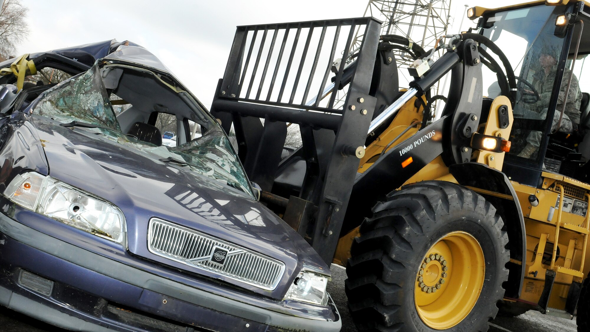 RAF MILDENHALL, England -- Staff Sgt. Ryan Johnson, 100th Logistics Readiness Squadron operator records and licensing NCO, positions a wrecked vehicle with a forklift here Feb. 16, 2011. Wrecked cars were placed at two exit gates to keep Team Mildenhall aware of the hazards of reckless driving and the dangers of vehicle rollover accidents. (U.S. Air Force photo/Senior Airman Tabitha M. Lee)