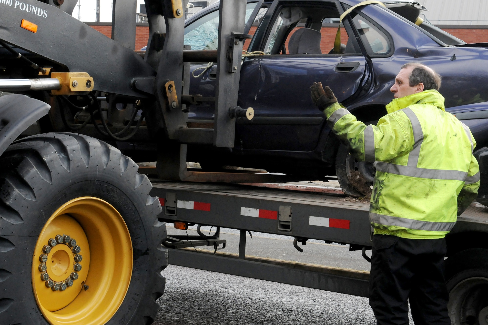 RAF MILDENHALL, England -- David Green, 100th Logistics Readiness Squadron training and validations operations manager, guides a forklift here Feb. 16, 2011. Wrecked cars were placed at two exit gates to keep Team Mildenhall aware of the hazards of reckless driving and the dangers of vehicle rollover accidents. (U.S. Air Force photo/Senior Airman Tabitha M. Lee)  