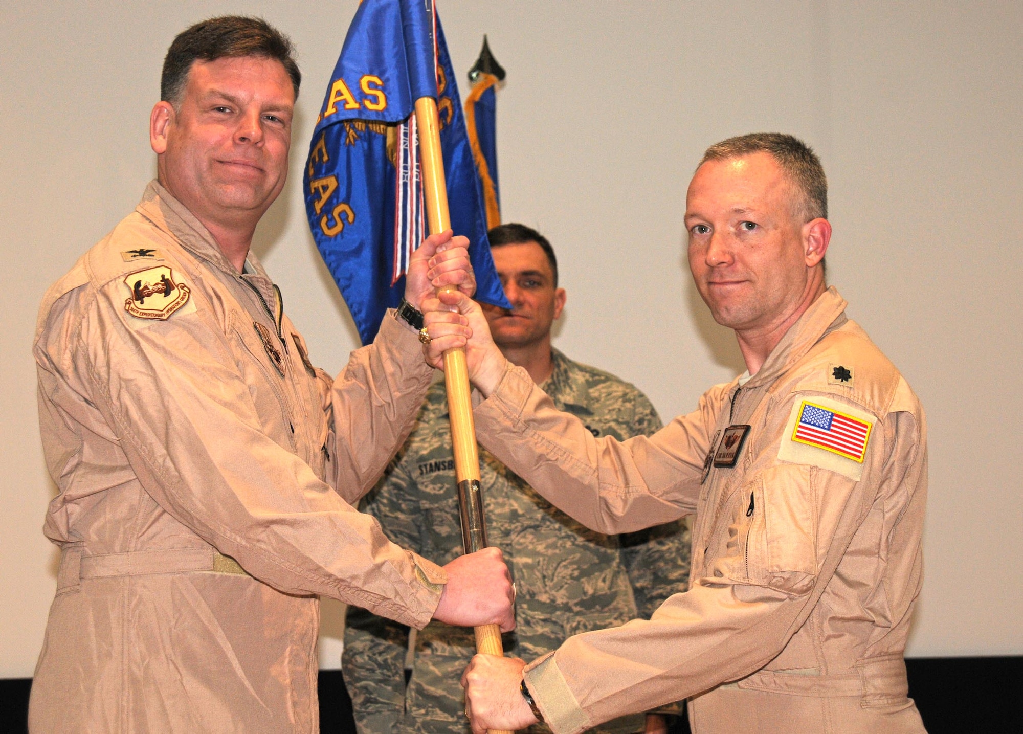 Col. Scott Brewer, 386th Expeditionary Operations Group commander, hands the 737th Expeditionary Airlift Squadron guidon to Lt. Col. Eric Halverson, the new commander of the squadron during a change of command ceremony Feb. 14, in an undisclosed location in Southwest Asia. Colonel Halverson assumed command from Lt. Col. David Kincaid, who will soon be redeploying. (U.S. Air Force photo by Staff Sgt. Patrice Clarke)