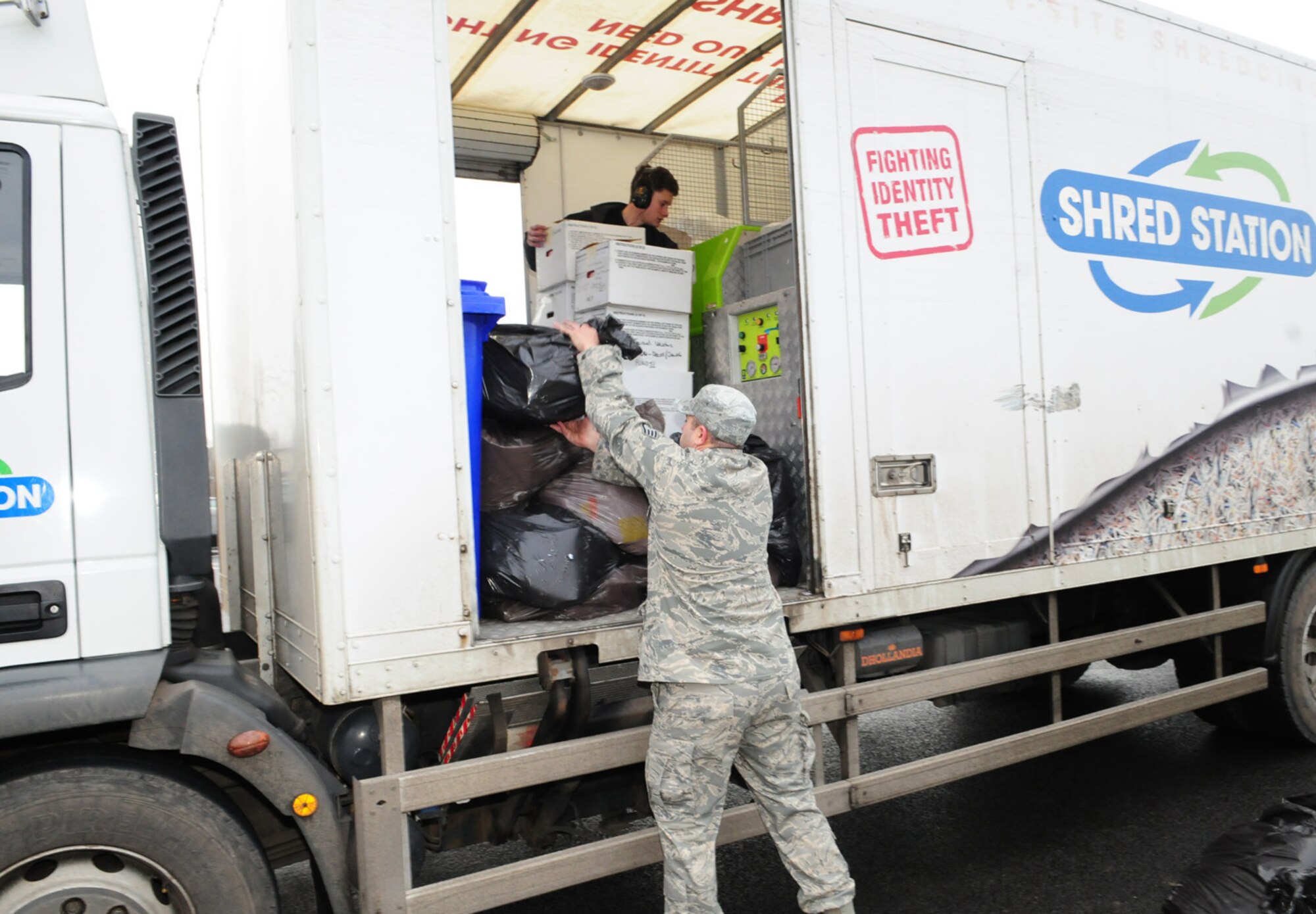 RAF MILDENHALL, England -- Staff Sgt. Eduardo Martin, 100th Comptroller Squadron, helps load bags of recycling onto a shredder truck Feb. 16, 2011, at the auto resale parking lot here, as Oliver Grice, contractor, loads paper into the shredder. Employees from around the base brought recycling to load into the industrial shredder, as an information protection measure. (U.S. Air Force photo/Karen Abeyasekere)
