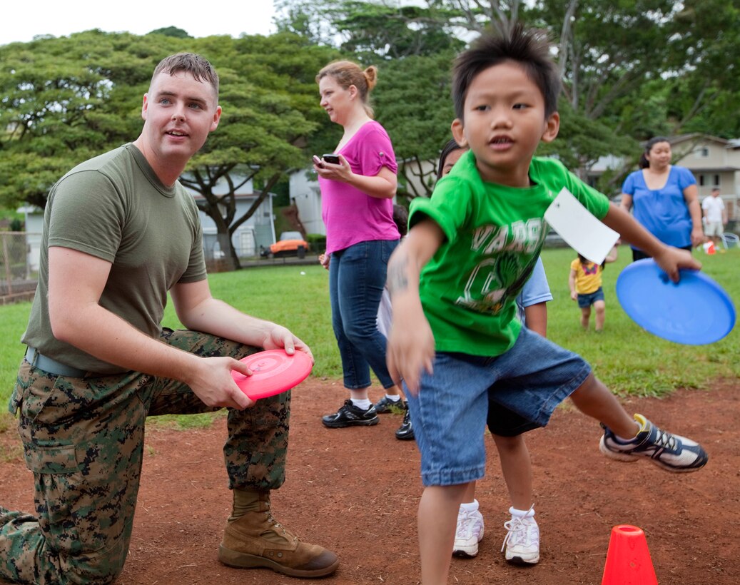 Cpl. Andrew Lahey, a tuba player with the U. S. Marine Corps Forces, Pacific Band, coaches a six-year-old student Feb. 18 at Palisades Elementary School, here, during the school’s annual sports day. Lahey was one of more than a dozen Marines who volunteered to assist the school in promoting physical fitness and give back to the community.