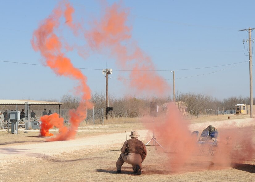 DYESS AIR FORCE, Texas – Staff Sgt. Dwight Daigle, 7th Operations Support Squadron, signals for air support with smoke Feb. 18 during a portrayal of a downed pilot at the cantonment area here. A dedication ceremony was held renaming the cantonment area Ray Rangel Air Base and celebrating Staff Sgt. Ray Rangel's life and commitment to Air Force core values. Sergeant Rangel lost his life more than five years ago while attempting to save three Soldiers trapped in an overturned and submerged Humvee in a canal in northern Iraq. There were fire trucks, explosive ordinance disposal specialists, security forces and ambulance equipment on display, as well as tents and other items for the public to see what deployed life is like. (U.S Air Force Photo/ Airman 1st Class Chelsea Cummings)