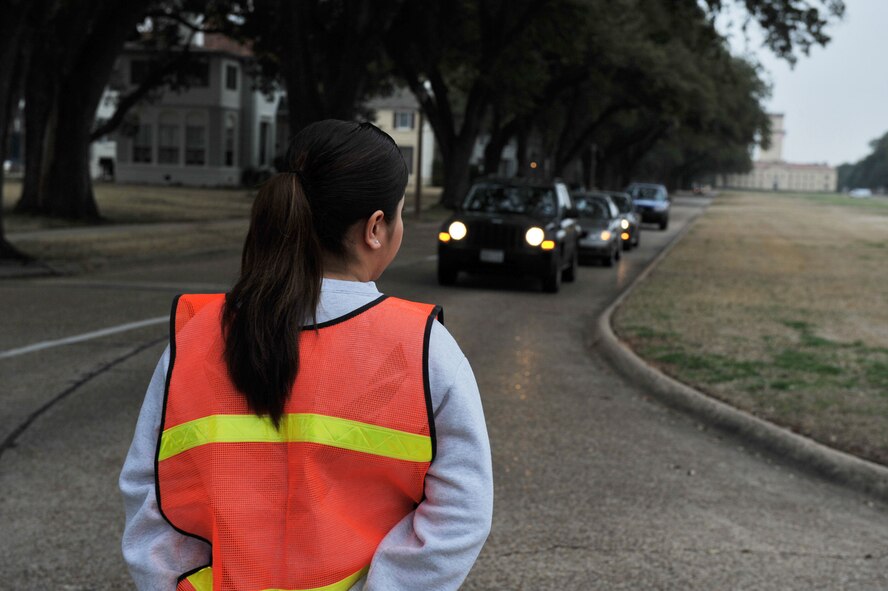 A volunteer for the 2nd Force Support Squadron stops traffic to allow participants in the "Bring Your Valentine" 5k Run to cross Barksdale Boulevard on Barksdale Air Force Base, La., Feb. 18. The Fitness Center host events similar to the 5k run once a month. (U.S. Air Force photo/Airman 1st Class Micaiah Anthony)(Released)