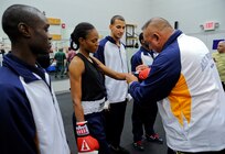 U.S.  Navy boxer Keston Williams (left), USS Laboon (DDG 58), watches as teammate, Master-at-Arms Rhonda McGee gets her gloves adjusted before competing in the Armed Forces Boxing Tournament Feb. 15 at Lackland Air Force Base, Texas. Army, Navy, Air Force and Marine Corps boxers winning in the Armed Forces Boxing Championships get a chance to compete for a spot on the Olympic team. (U.S. Air Force photo/Senior Amn. Marleah Miller)