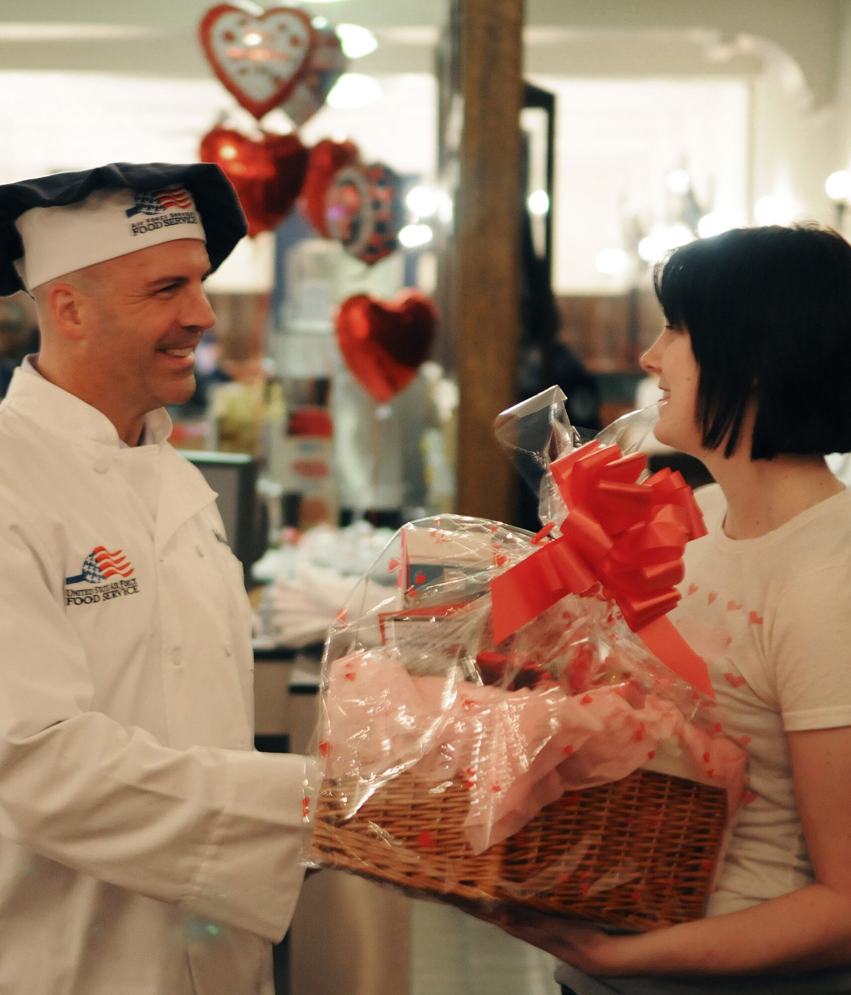 RAF MILDENHALL, England -- Col. Chad Manske, 100th Air Refueling Wing commander, presents a gift basket to Airman 1st Class Kathryn Merritt, 100th Logistics Readiness Squadron at the Gateway Dining Facility's Valentine's Dinner Feb. 14, 2011. Every customer of the dinner was given a ticket and one male and one female winner was drawn from random for two gift baskets. (U.S. Air Force photo/Staff Sgt. Thomas Trower)