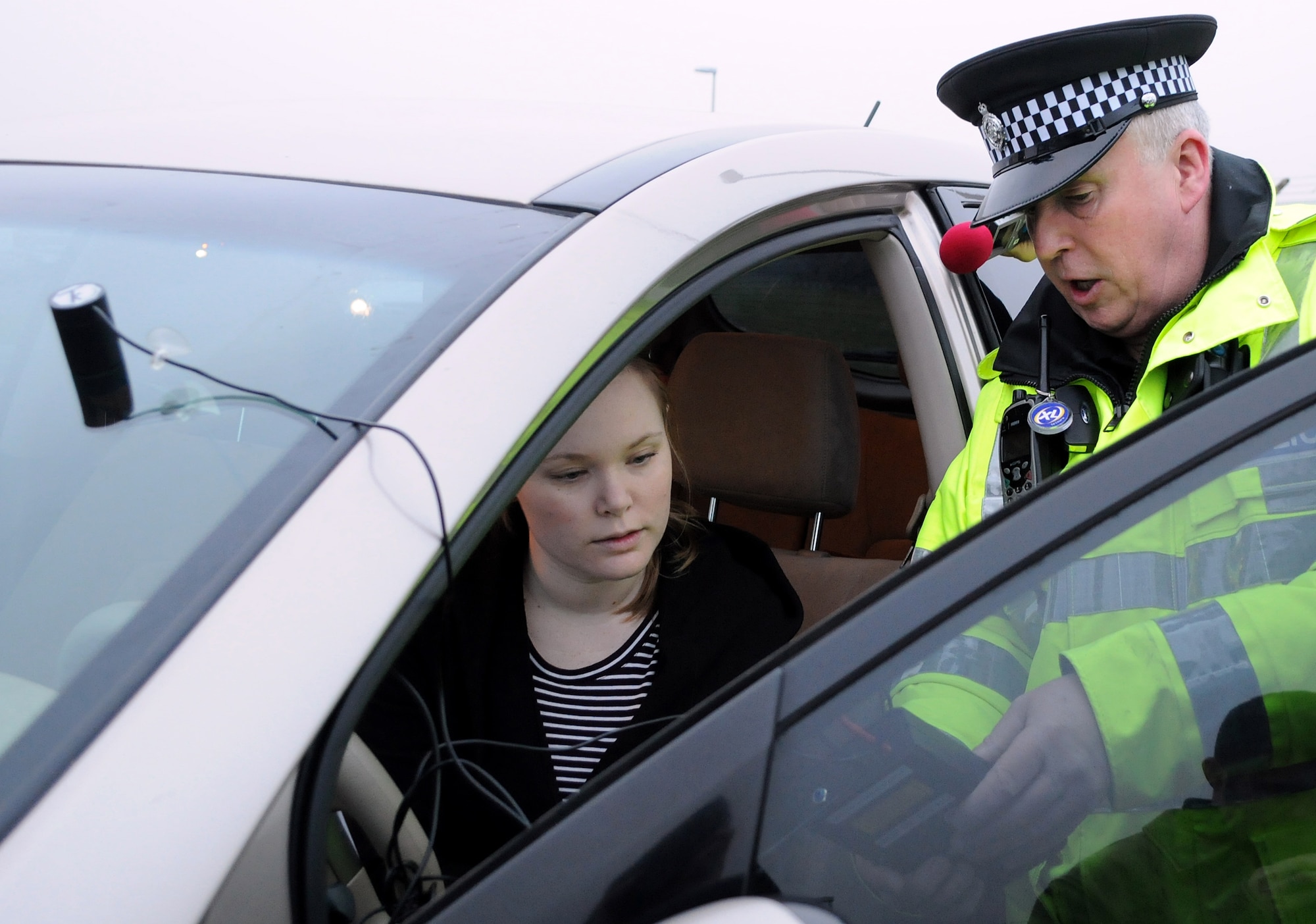 RAF MILDENHALL, England -- Police Constable Paul Glover, Ministry of Defence Police RAF Mildenhall, uses a photoptic vehicle tint tester to show Melissa McKencie, 100th Mission Support Group, the visible light transmission through her vehicle windshield here Feb. 18, 2011.  United Kingdom law requires windshields to have a minimum light transmission of 75 percent and front-side windows 70 percent. Suffolk Police are carrying out a 30-day amnesty all over Suffolk and are offering free VLT tests. However, if stopped after March 9, 2011, vehicle-owners will be prosecuted. (U.S Air Force photo/Senior Airman Tabitha M. Lee)