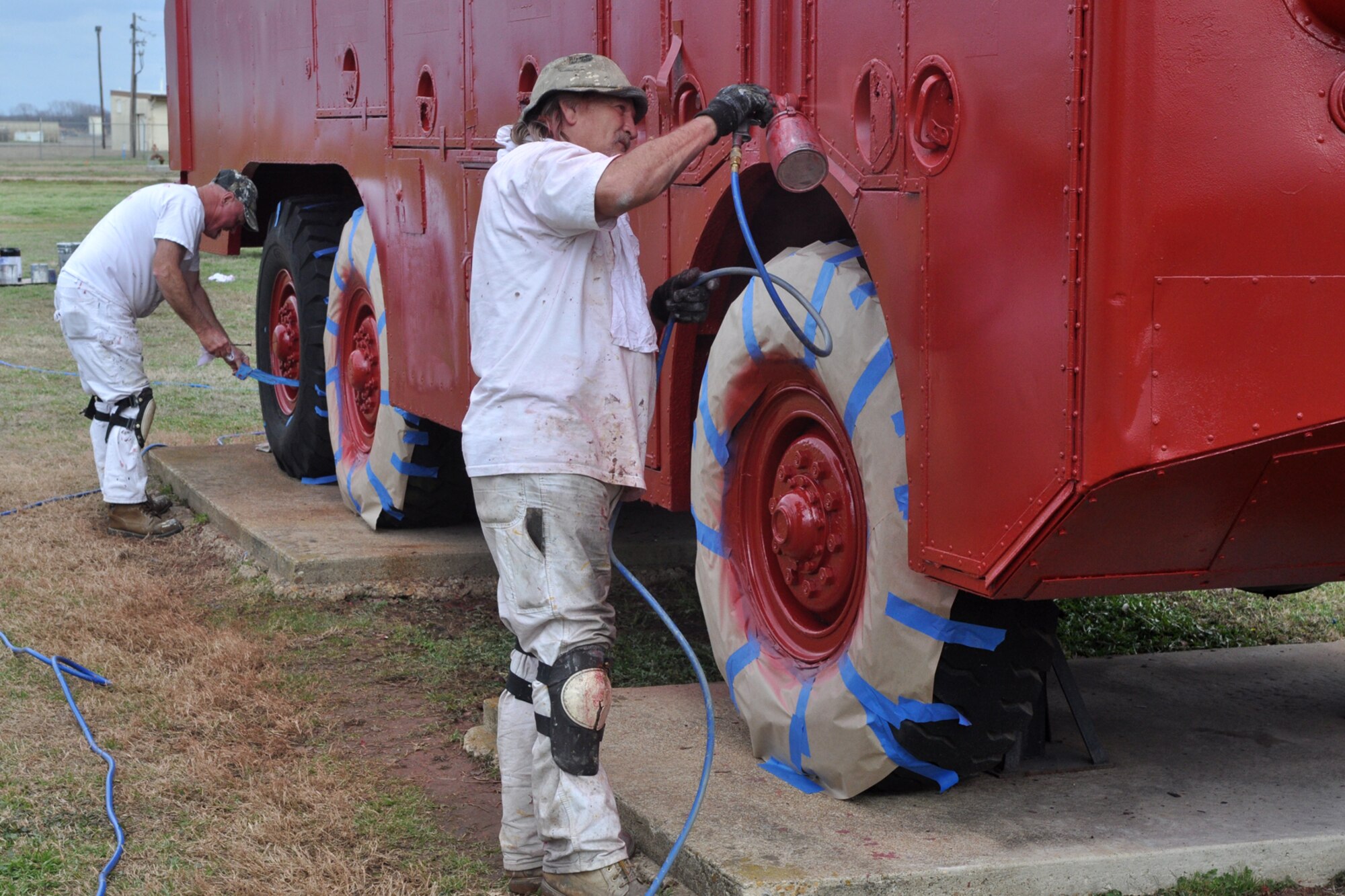 Painter Don Manning sprays another coat over an O-11B Aircraft Rescue and Fire Fighting (ARFF) truck as Ben Williford removes masking tape from the wheels of the vintage emergency vehicle at Barksdale Air Force Base, La., Feb. 16, 2011. The painters are part of a restoration crew that has been painting a number of the outdoor static displays that are part of the 8th Air Force Museum at Barksdale. The O-11B was in service to the U.S. Air Force from the late 1950s to the mid 1970s. It was used under any climatic conditions for combating aircraft fires, providing fire protection services for unconventional fuel fires, aircraft maintenance and servicing operations, and support of the Air Force structural fire fighting units.  The painting project is being undertaken by Affiliated Western in Fort Worth, Texas, and started in Sept 2010. Their work is scheduled to be completed next week.  (U.S. Air Force photo/Tech. Sgt. Jeff Walston)